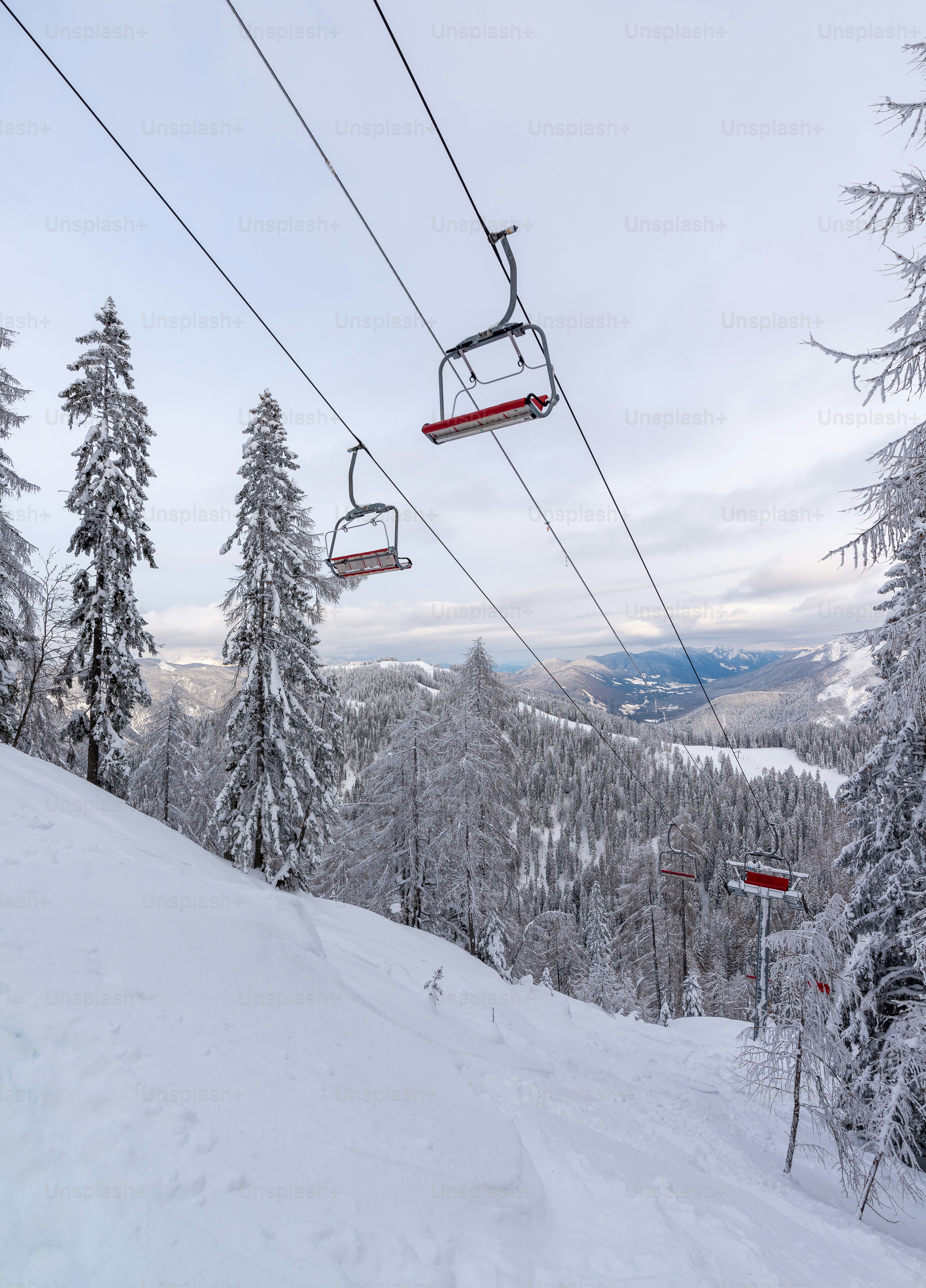 Ski lift chairs ascend a snow-covered mountain slope.