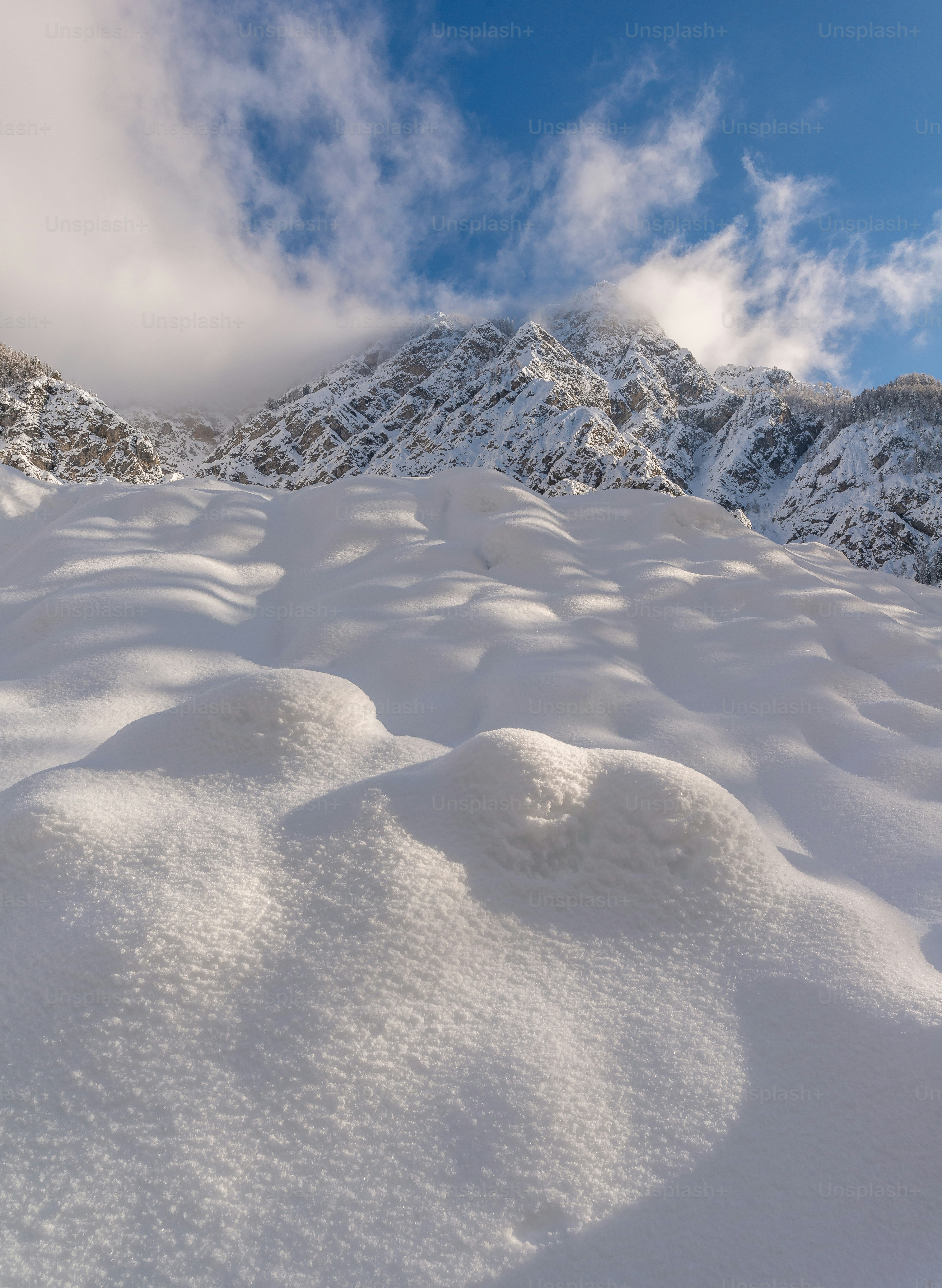 Snowy mountain landscape under a cloudy blue sky