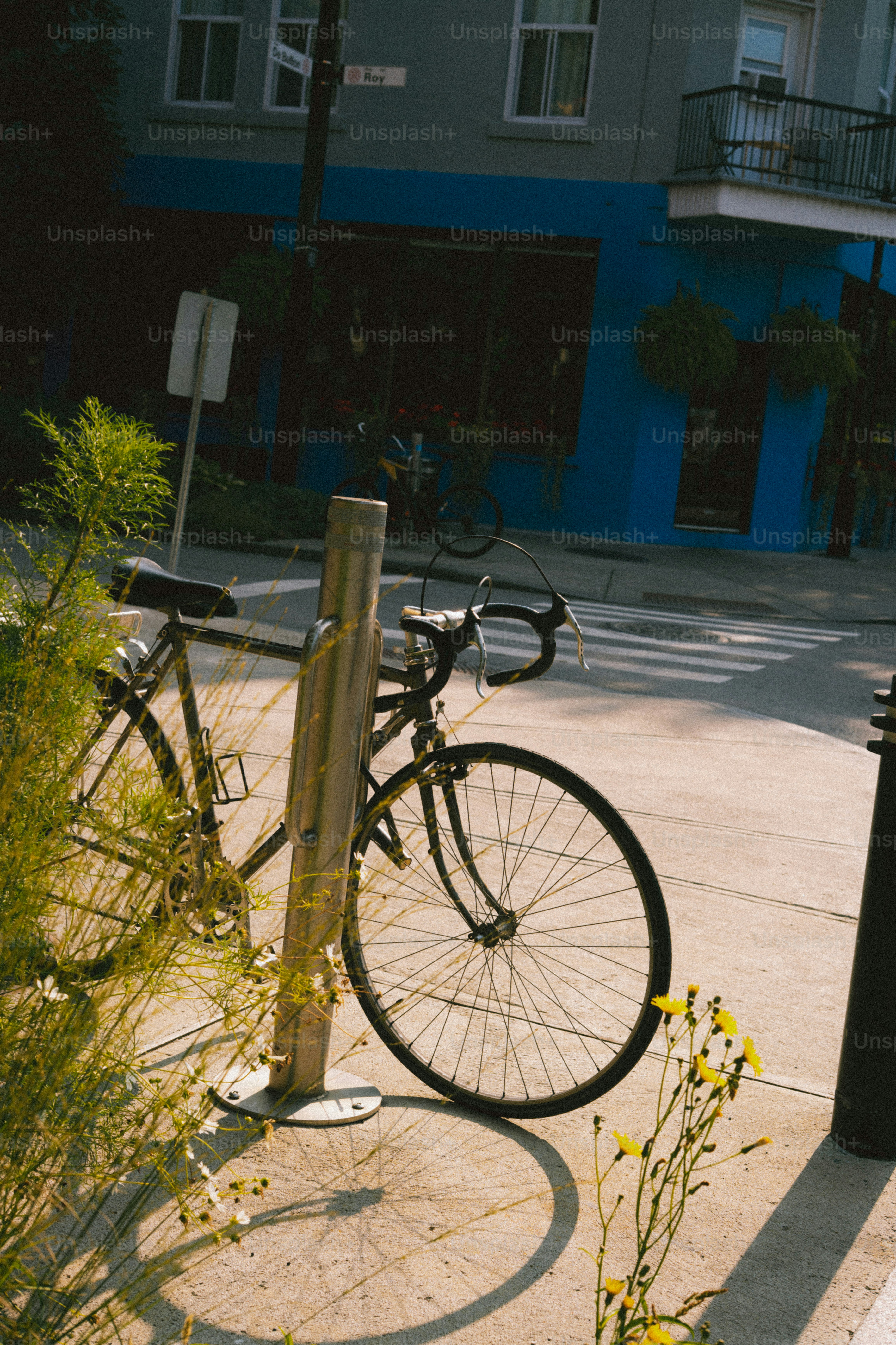 A bicycle parked on a sunny street corner.