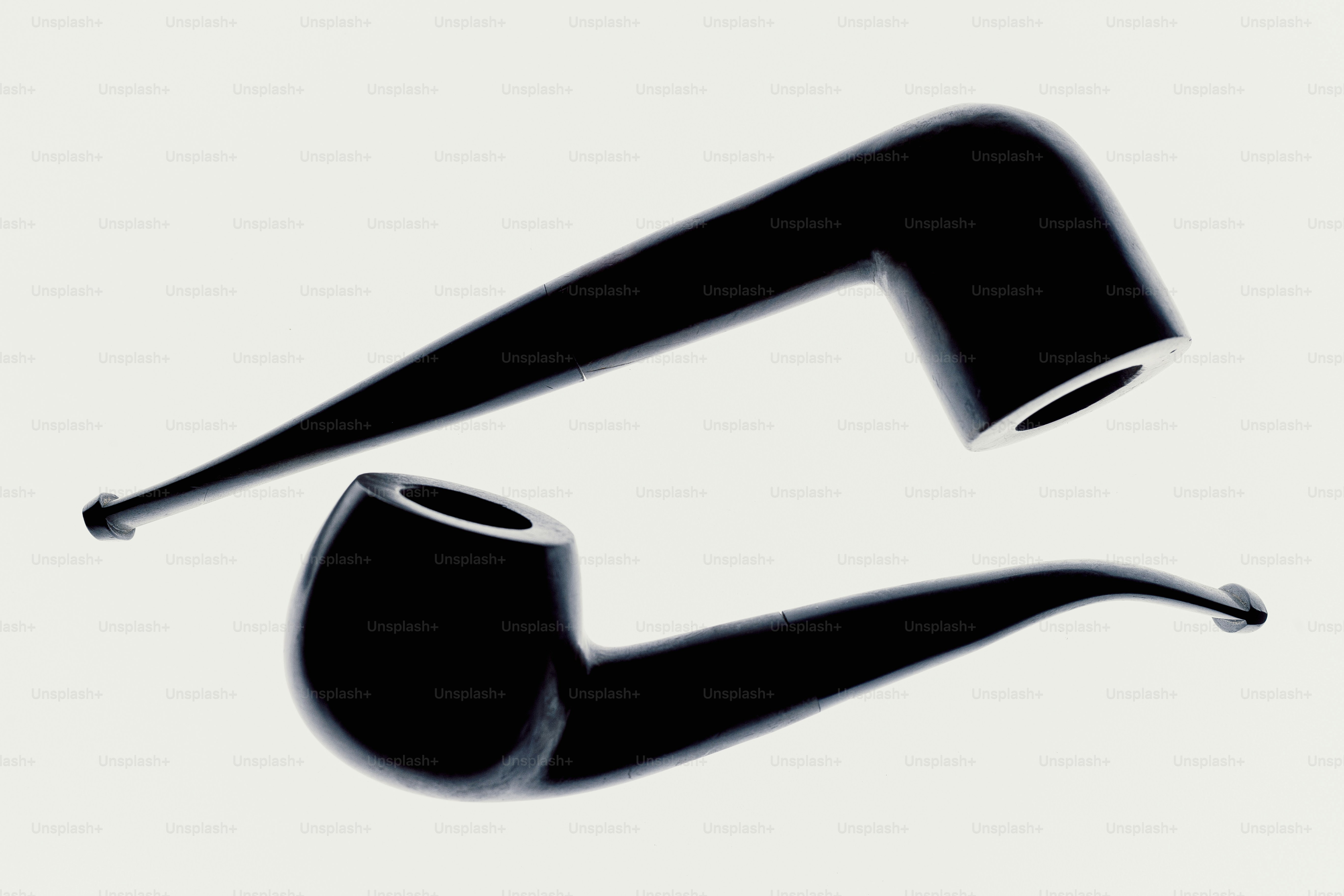 Two black smoking pipes on a white background