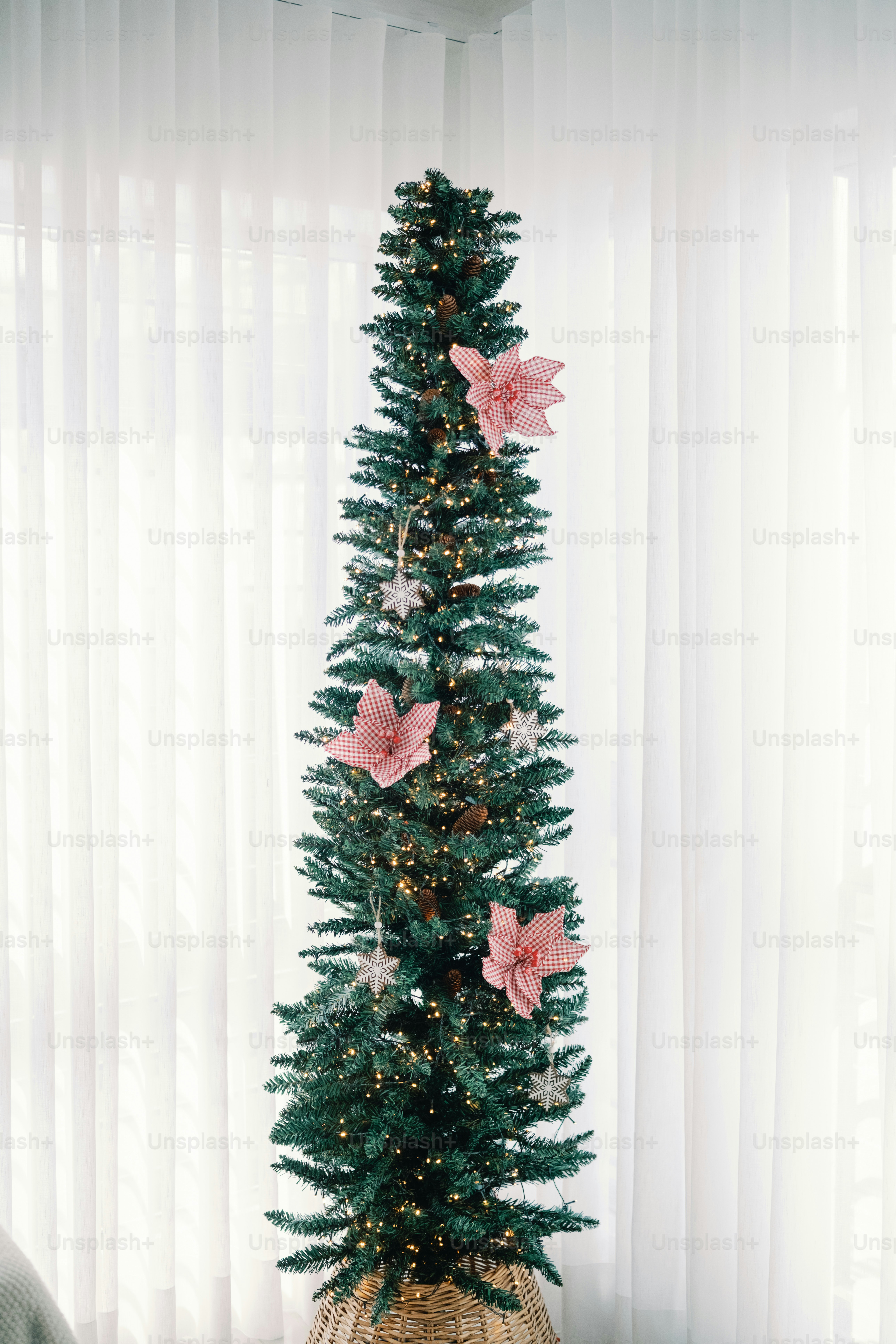 Ein hoher, schlanker Weihnachtsbaum, geschmückt mit rosa Blumen.