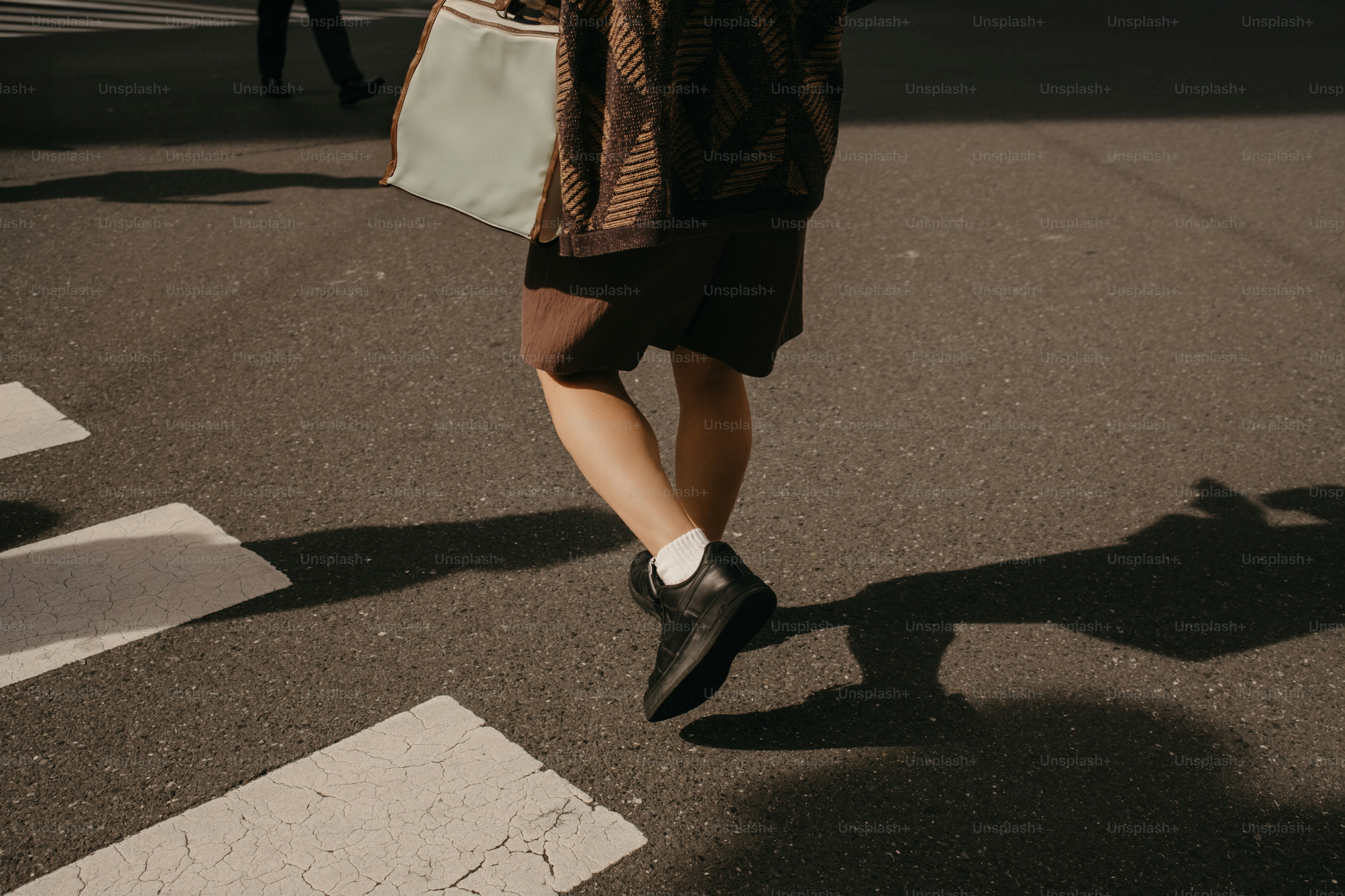 Person, die an einem sonnigen Tag über einen Zebrastreifen geht