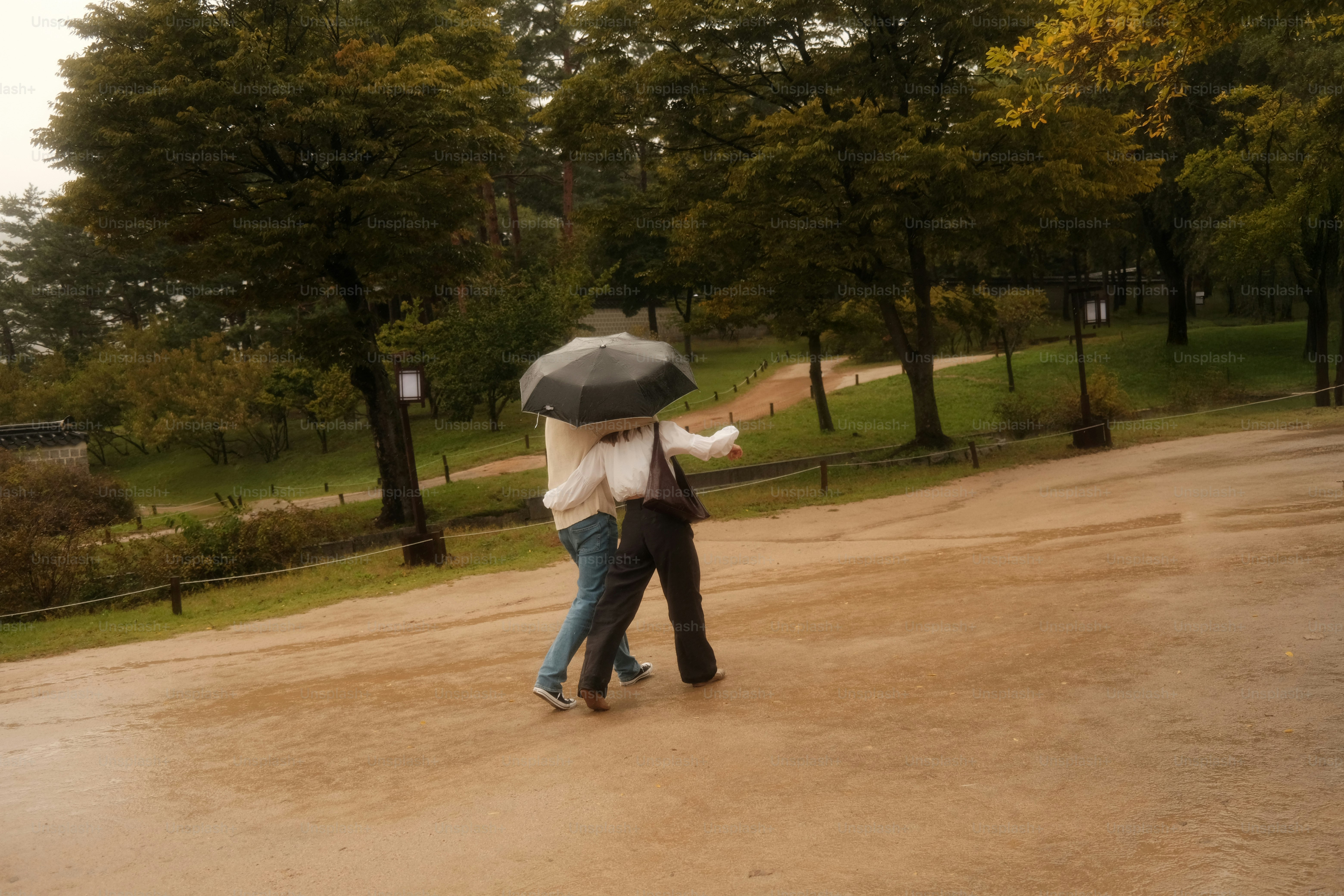 Zwei Personen teilen sich einen Regenschirm im Regen.
