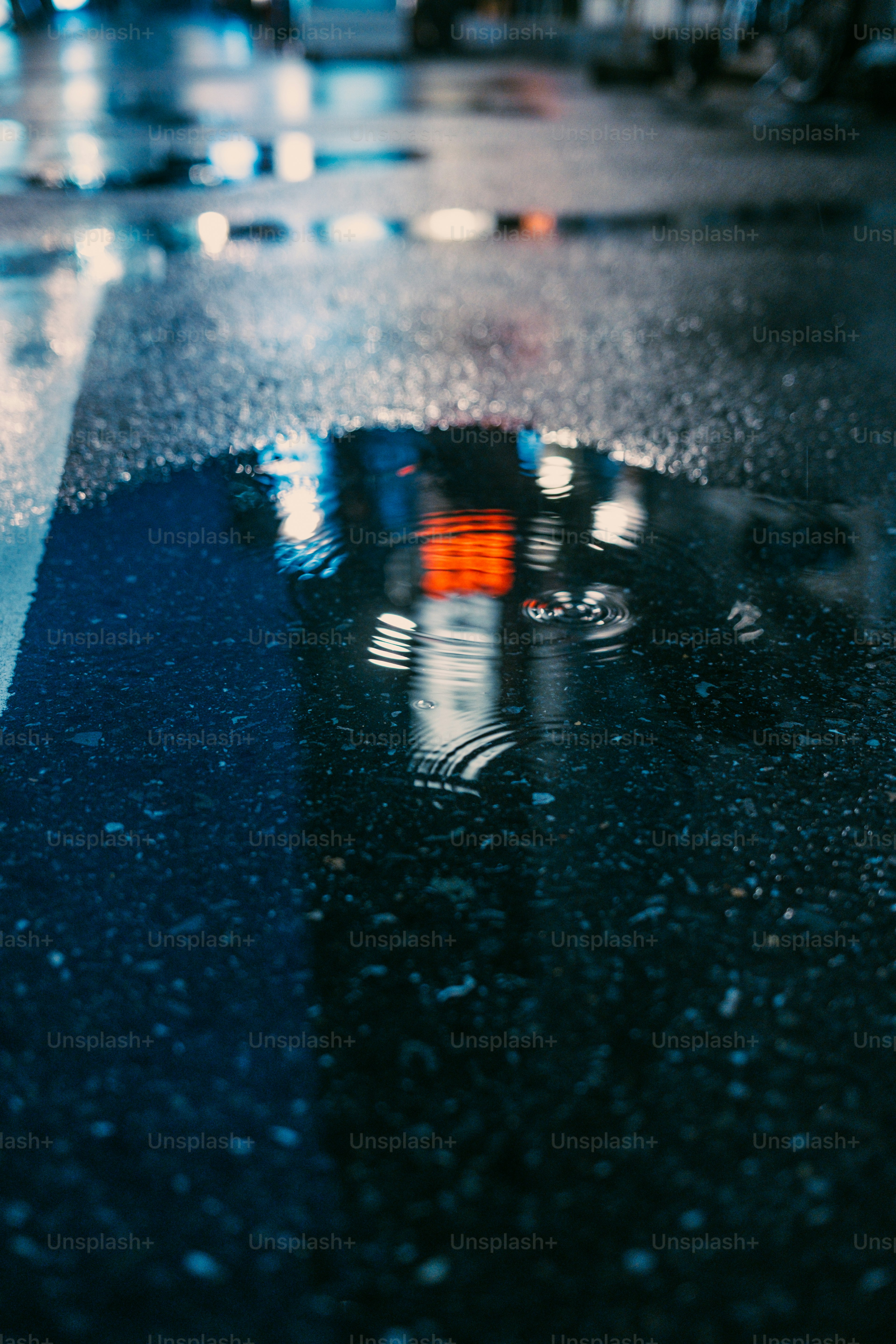 Stadtlichter spiegelten sich in einer nassen Pfütze auf der Straße wider