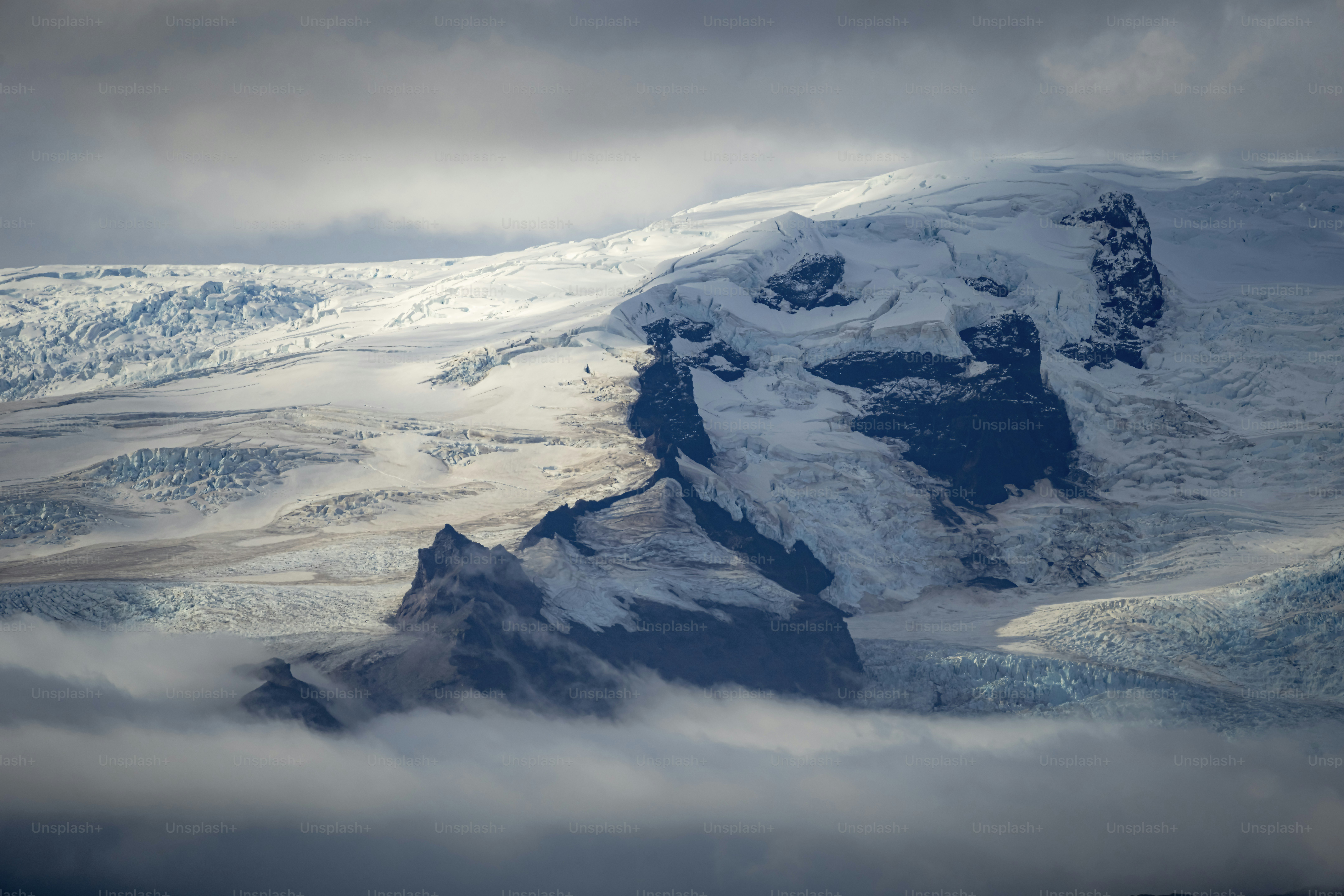 Snow-covered mountain peak emerging from clouds.