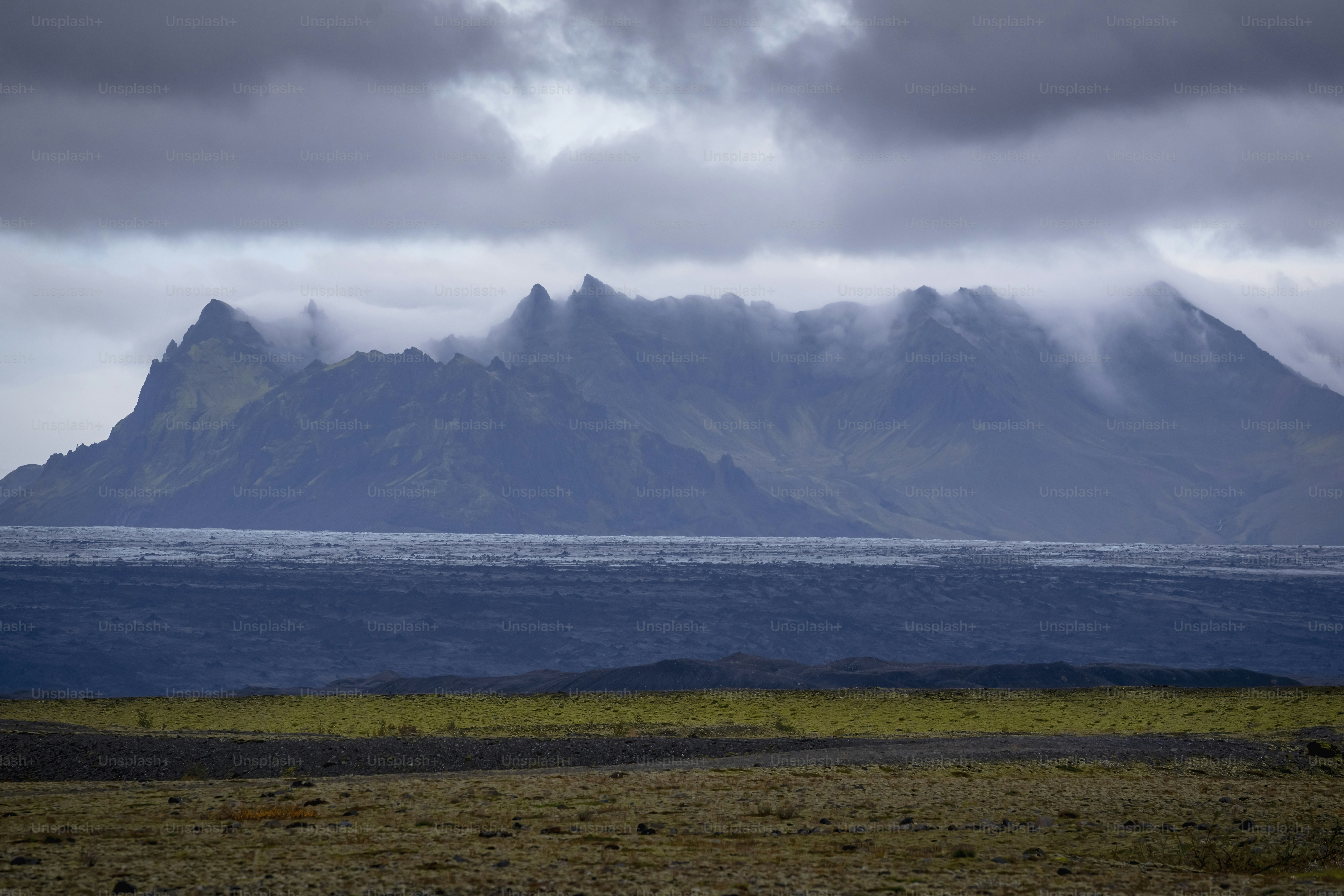 Misty mountains rise above a dark, rocky plain
