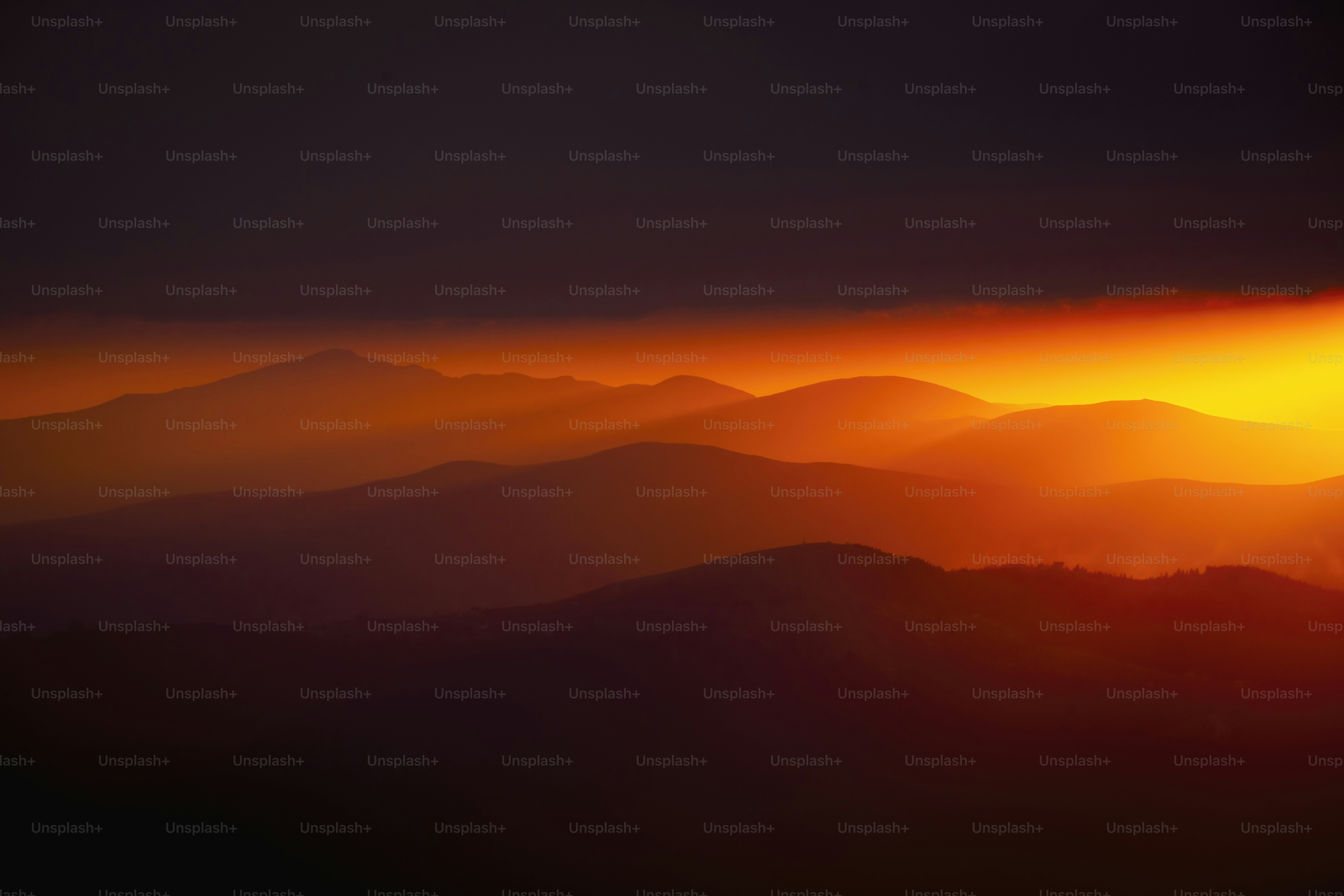 Silhouetted mountain range at sunset with vibrant orange glow.