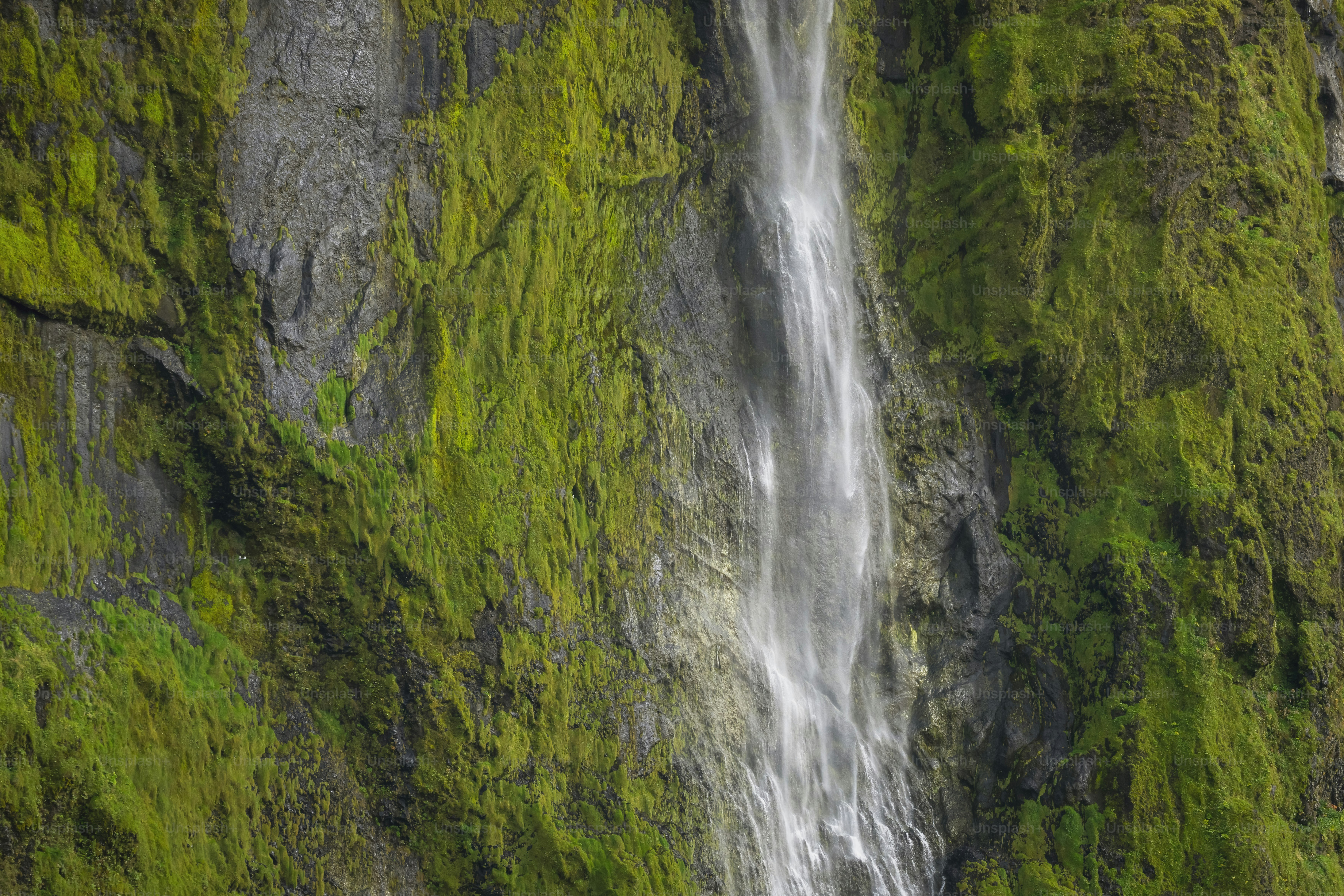 Waterfall cascading down a moss-covered rock face