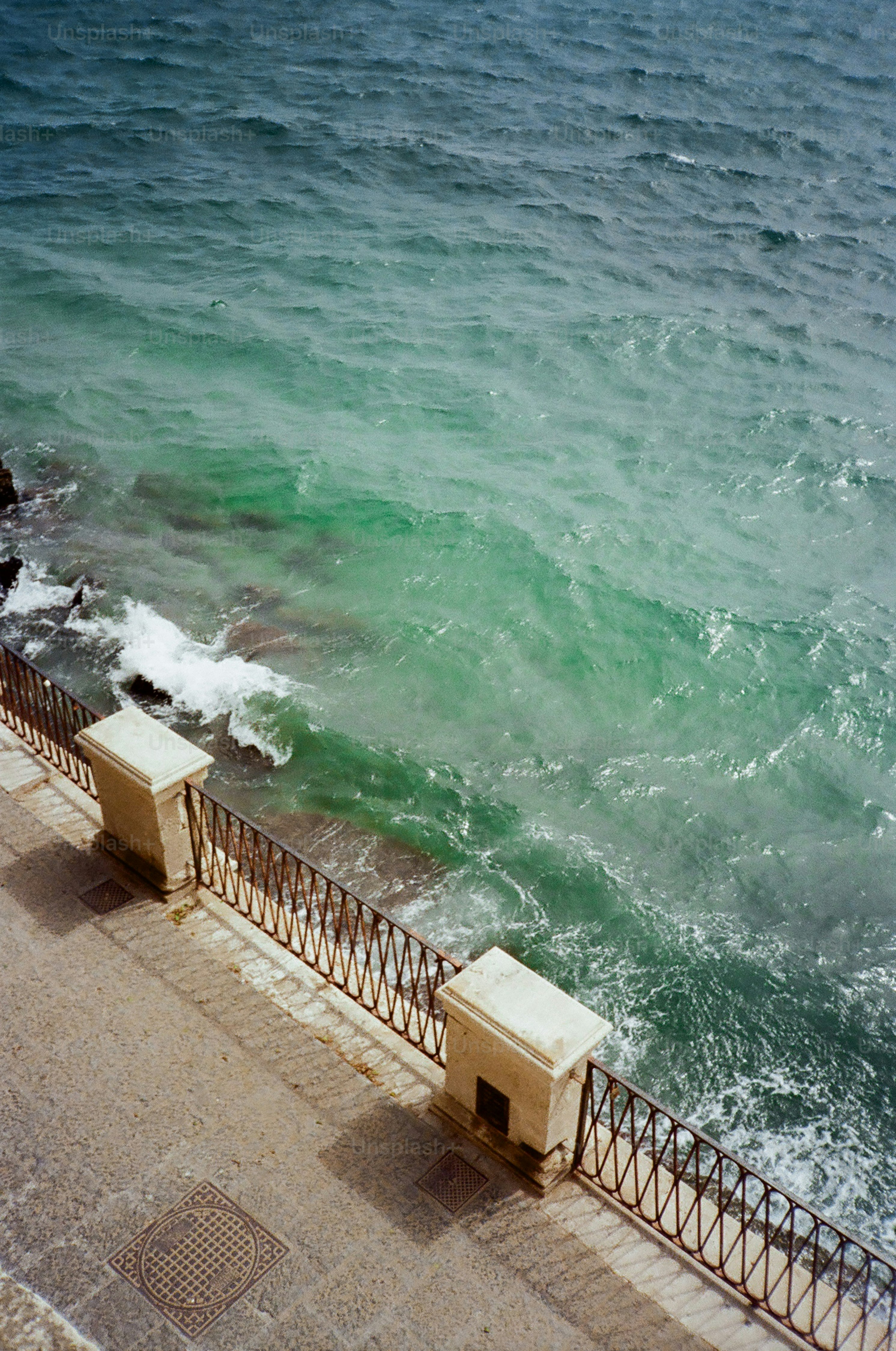Waves crash against a rocky shore with a walkway.