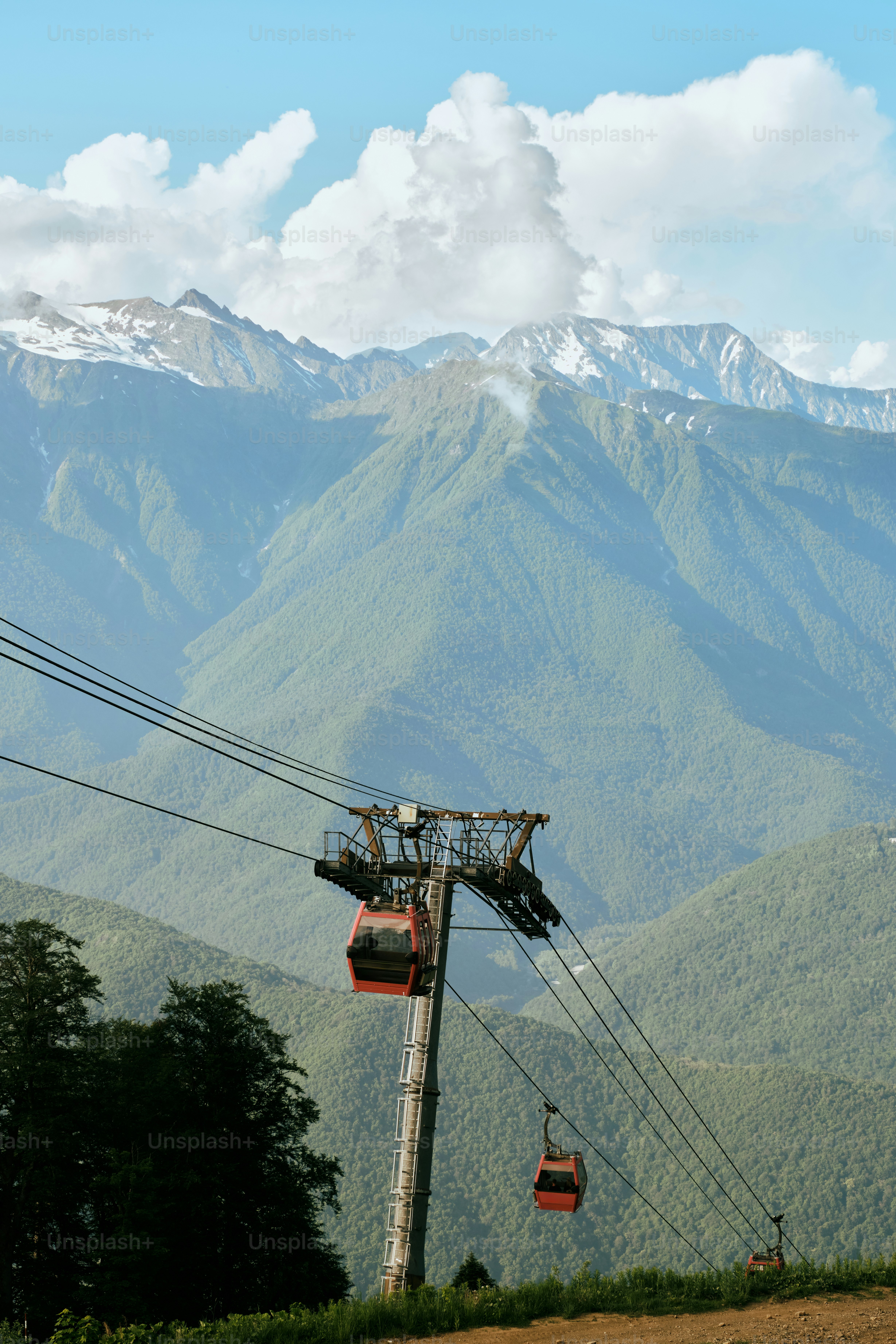 Cable cars ascend a mountain range with snowy peaks.