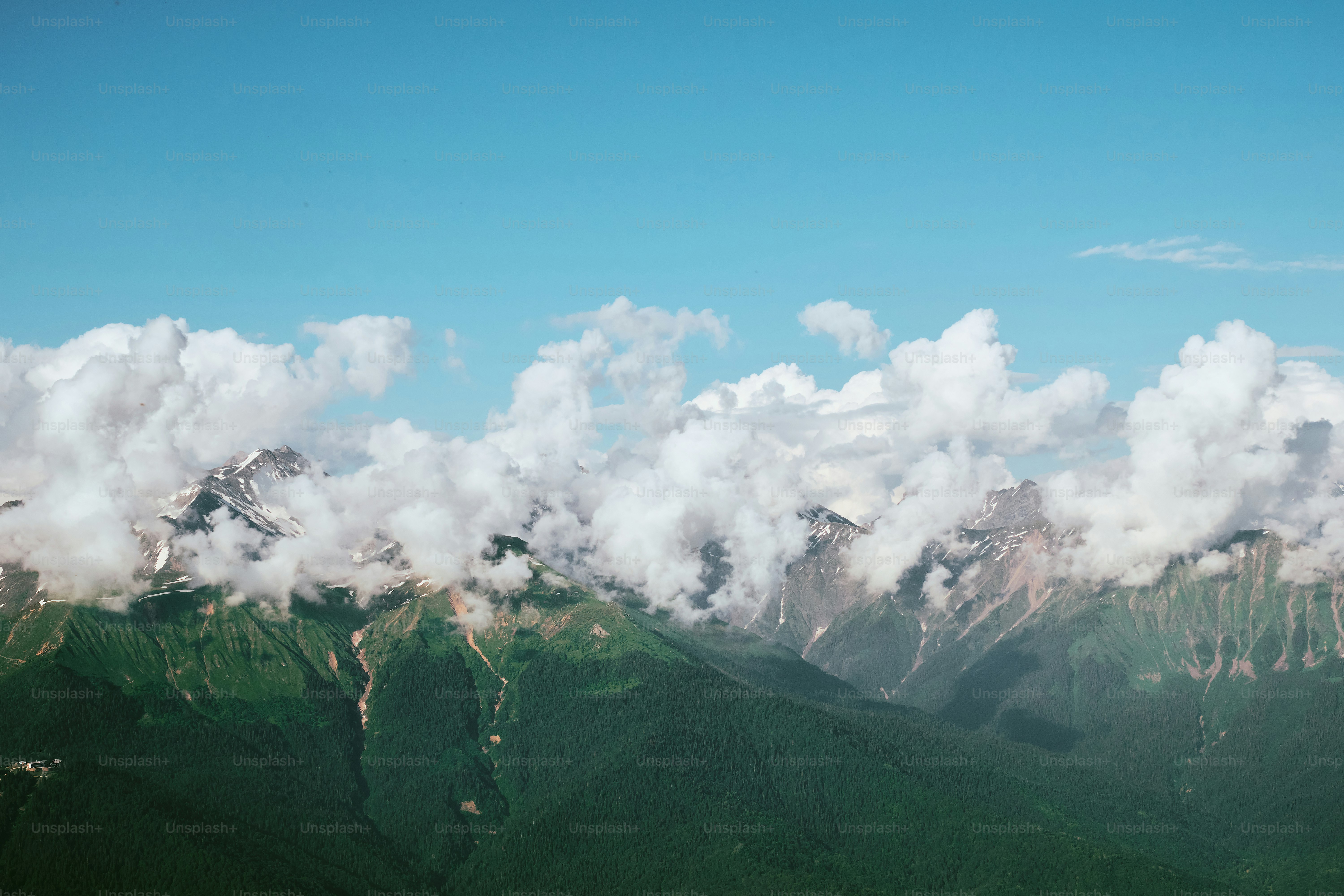 Nuages duveteux sur des montagnes vertes sous un ciel bleu