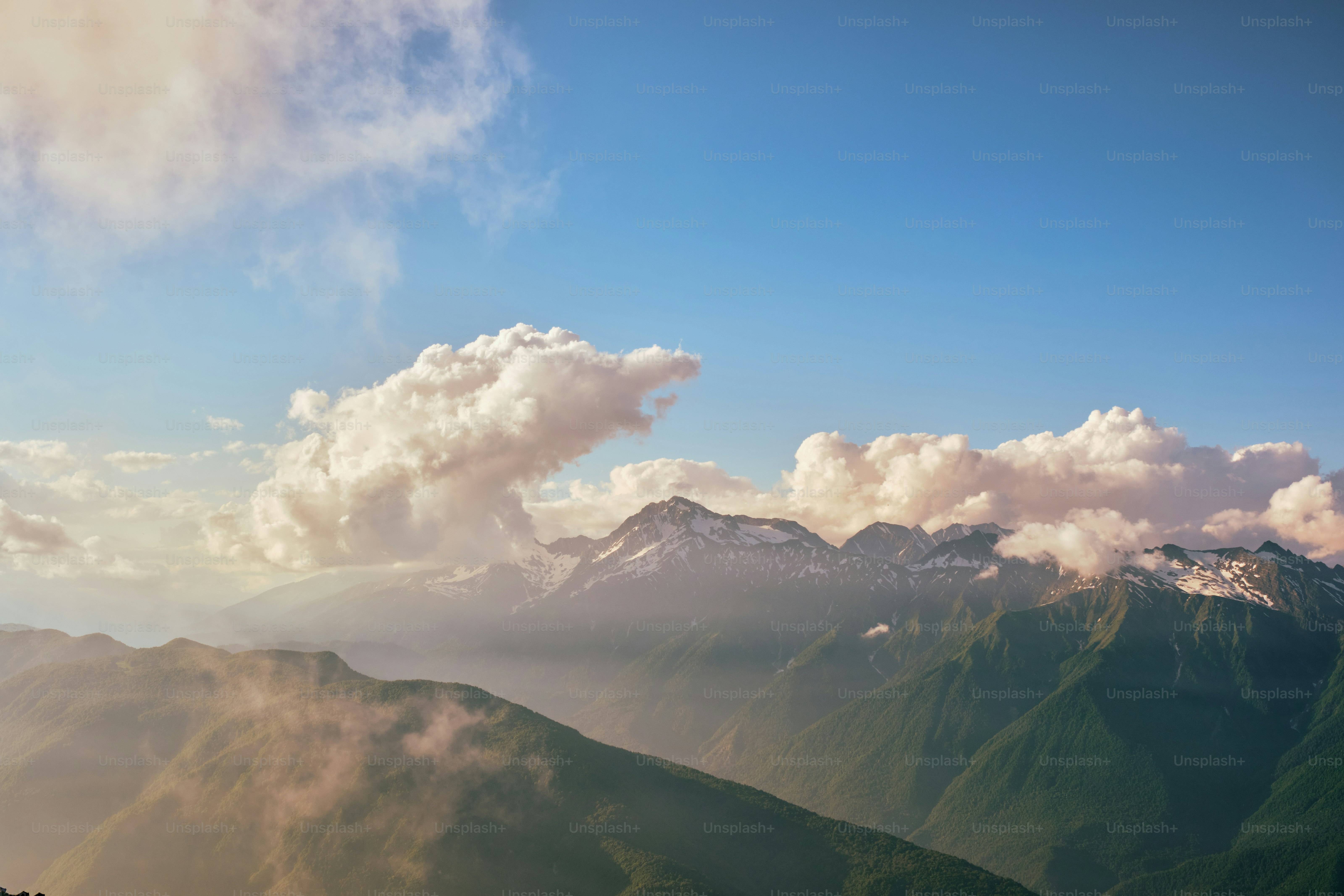 Chaîne de montagnes brumeuse sous un ciel bleu avec des nuages