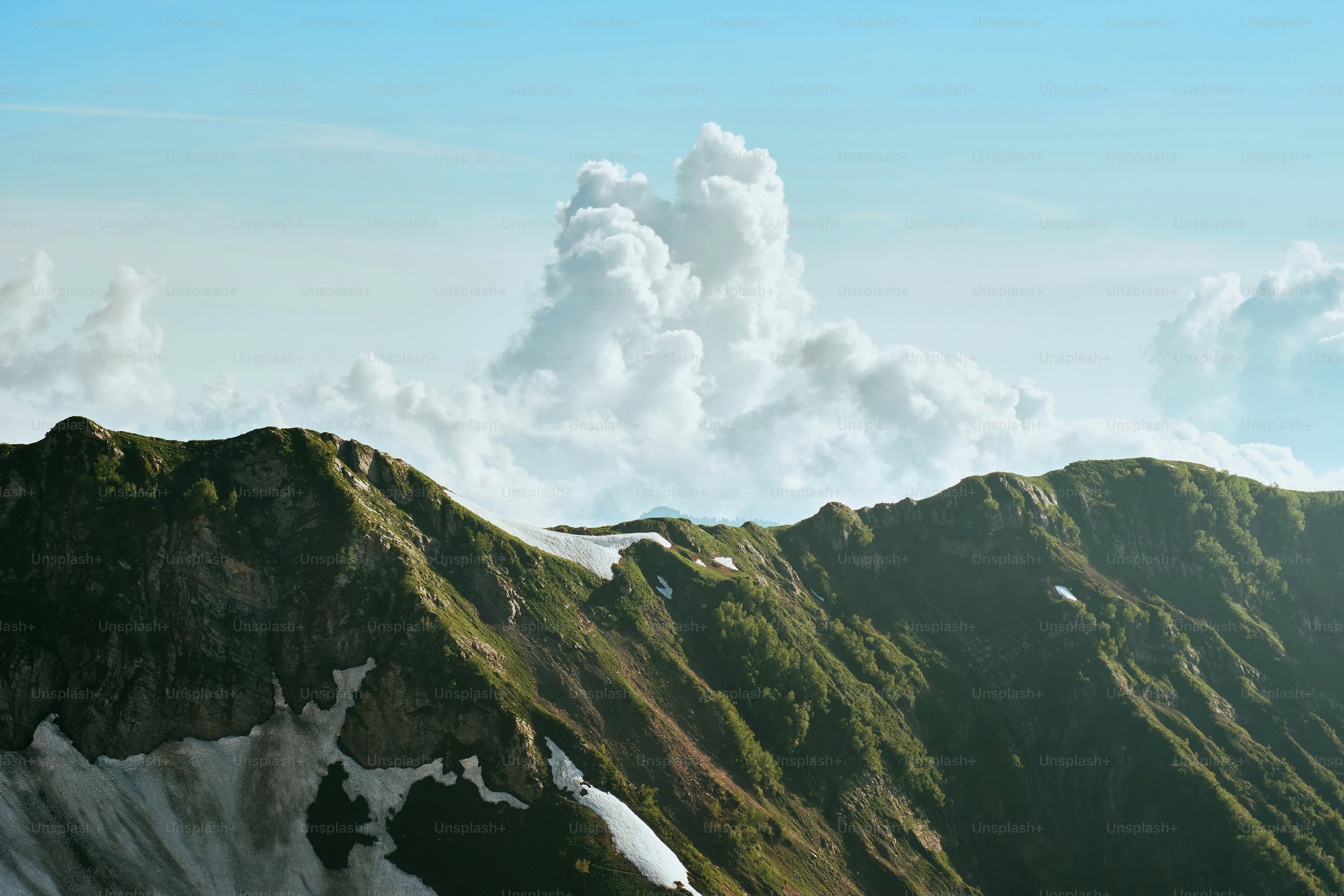 Majestueuse chaîne de montagnes avec des pentes enneigées et verdoyantes.