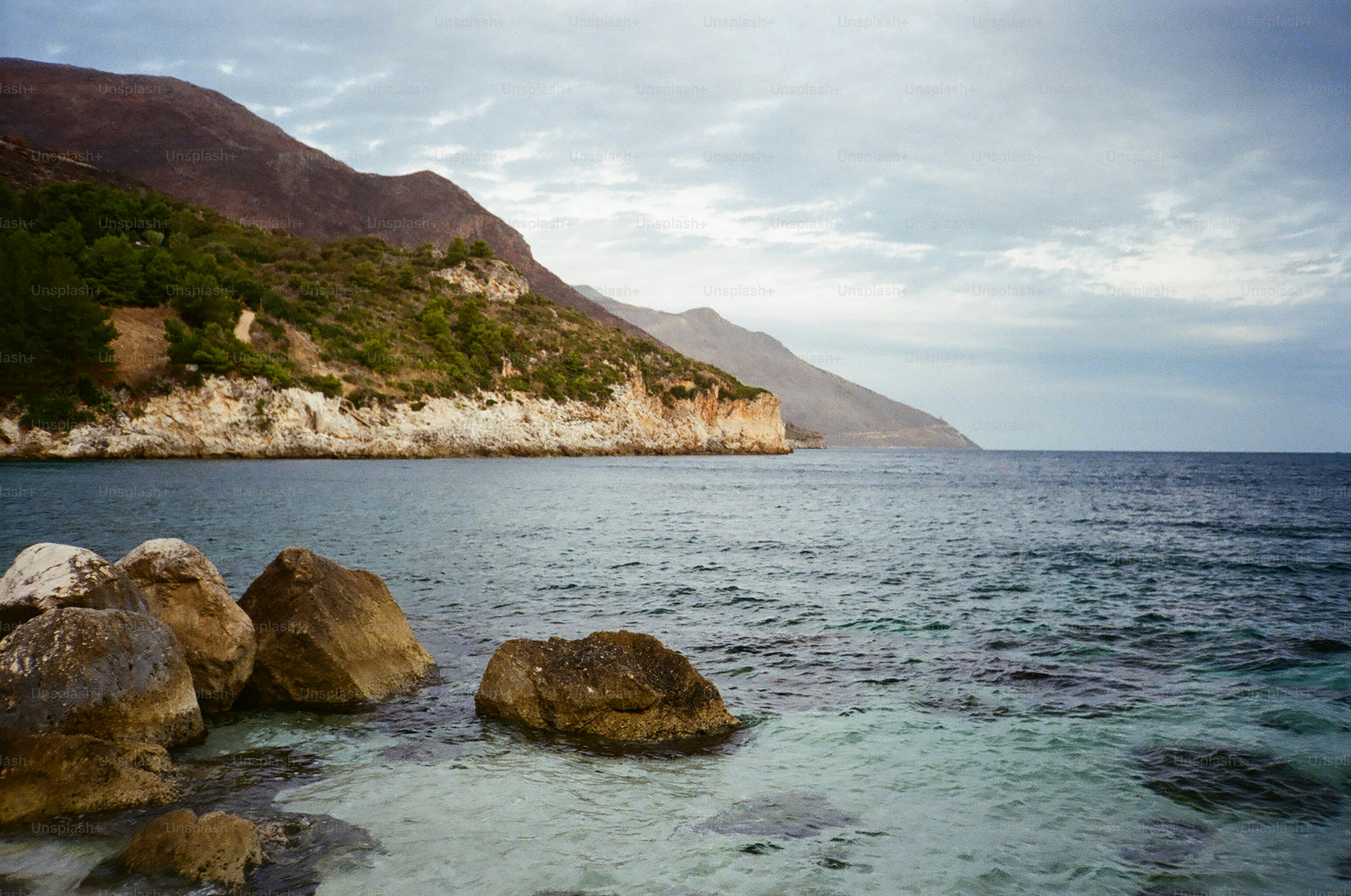 Costa rocosa con aguas turquesas claras y colinas verdes. foto – Imagen ...