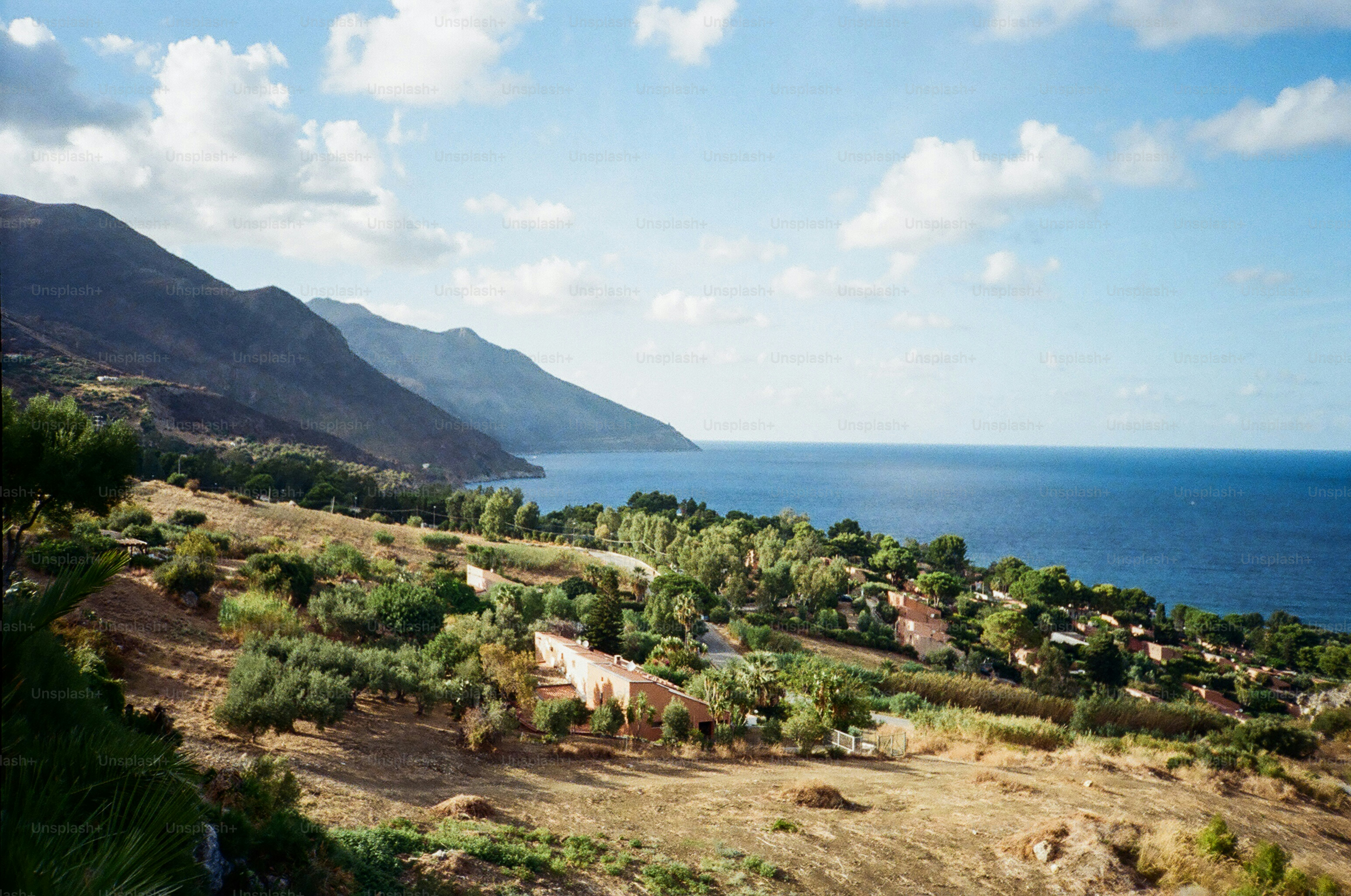 Coastal landscape with mountains and blue ocean under sky.