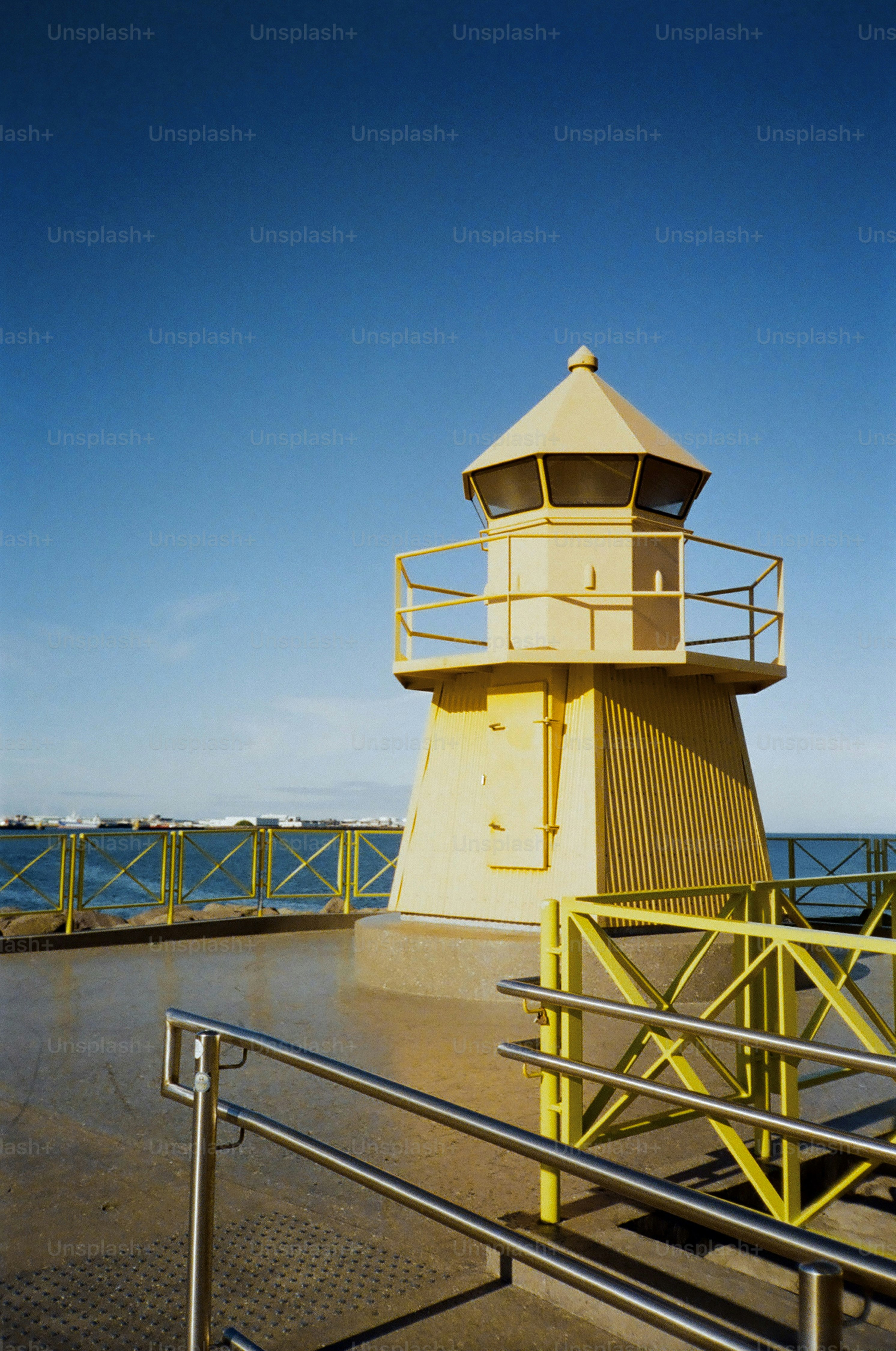 Yellow lighthouse on a pier with blue sky