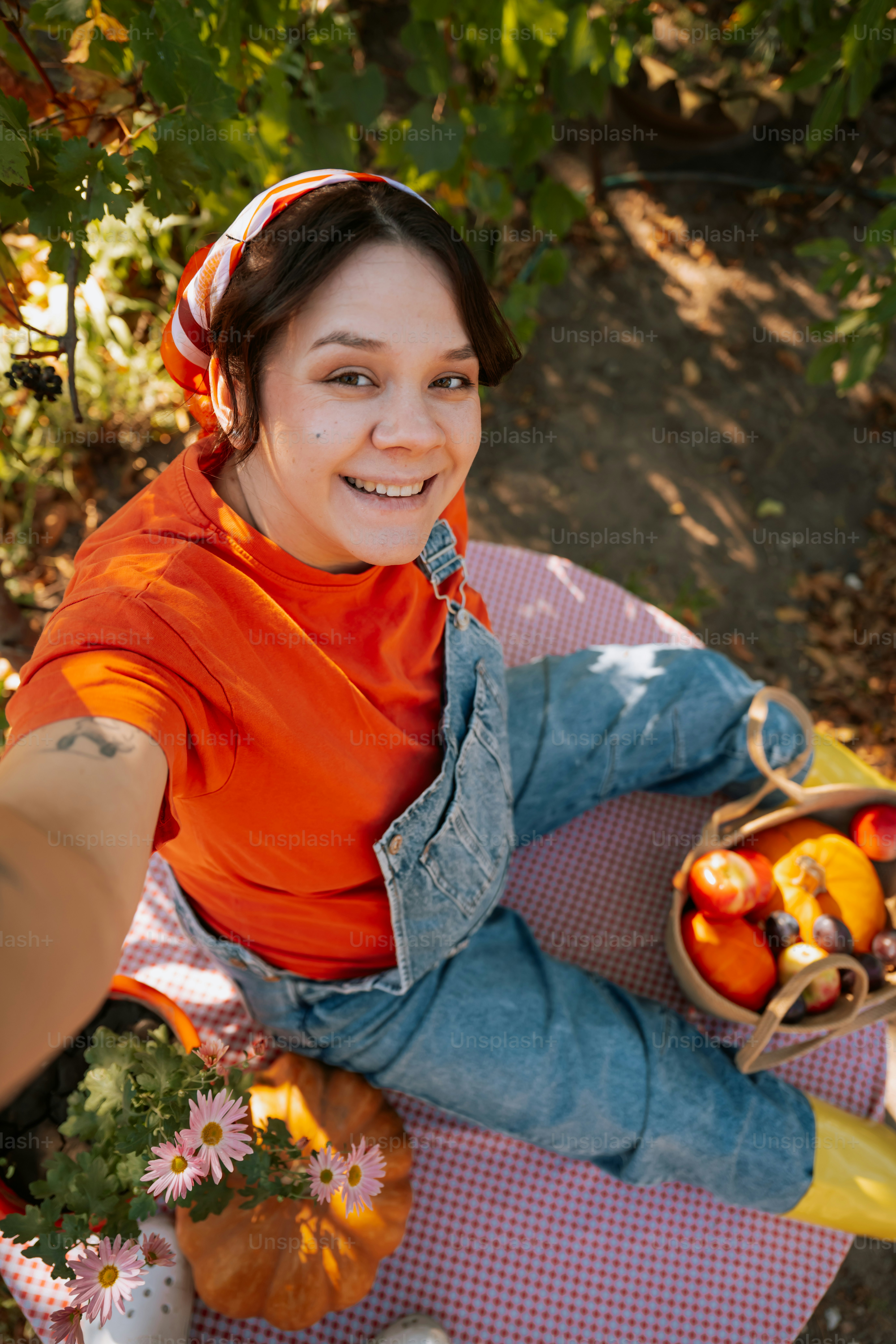 Mujer sonriendo con calabazas y flores