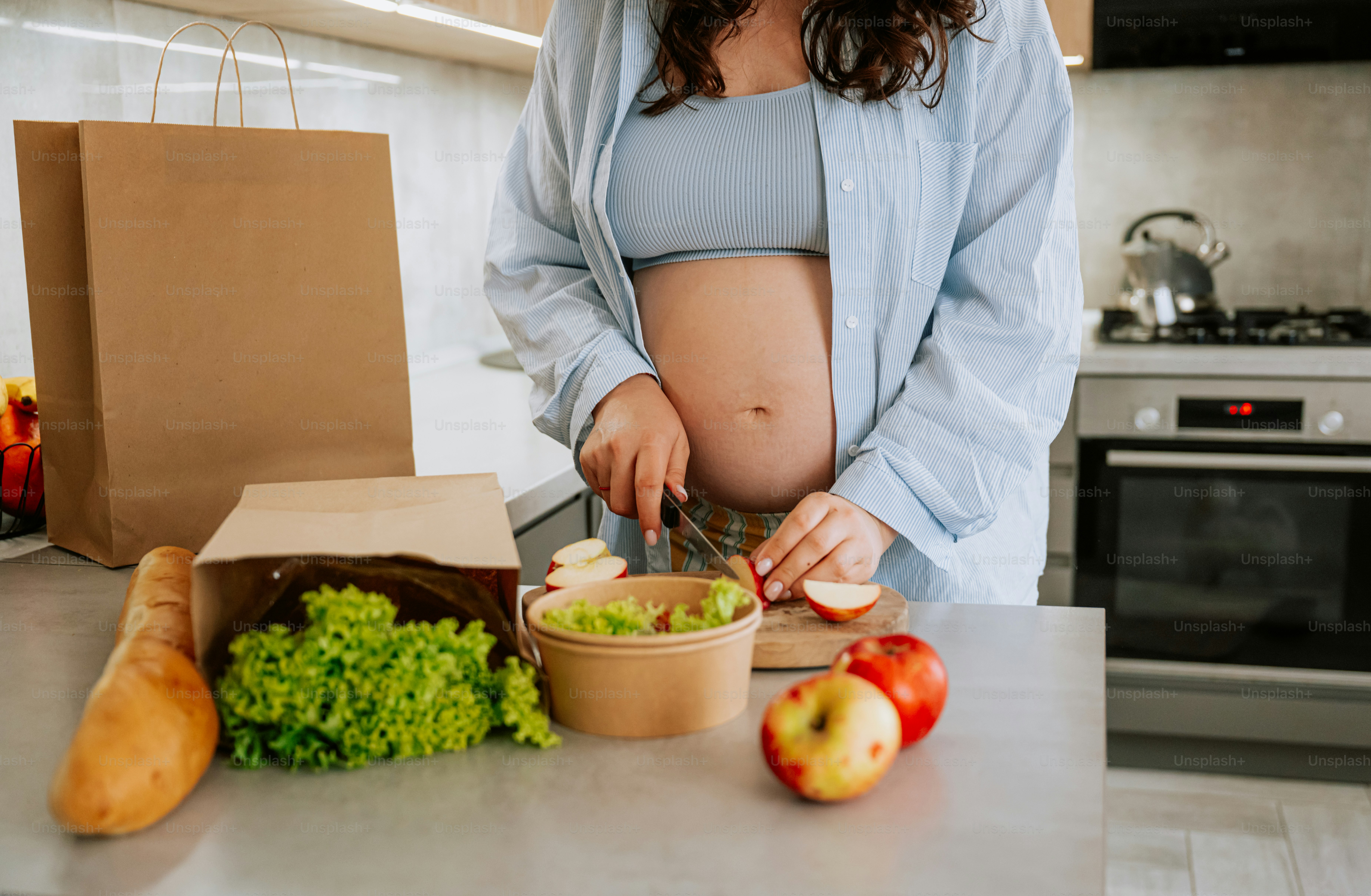 Mujer embarazada preparando comida fresca en la cocina.