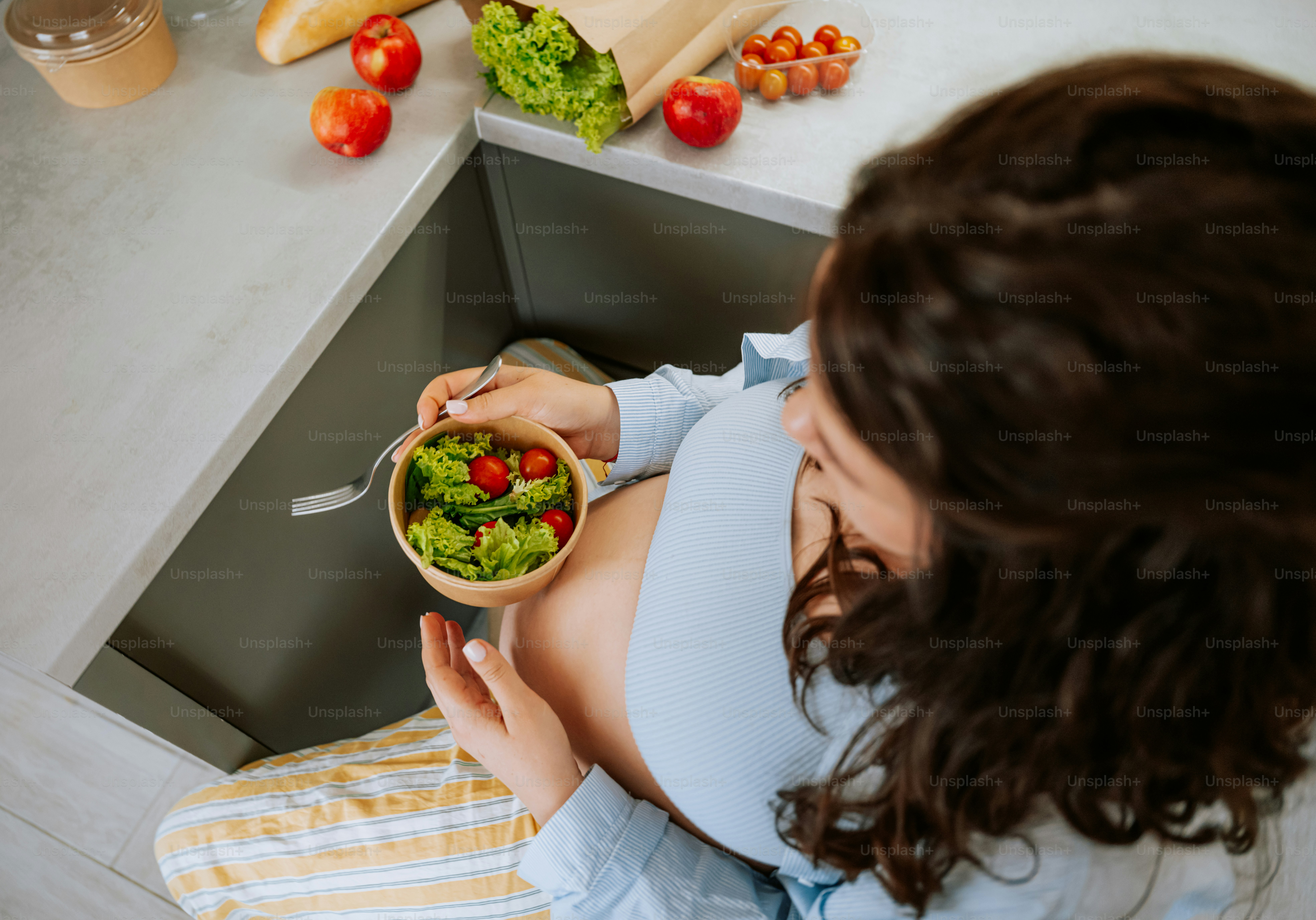 Mujer embarazada comiendo una ensalada saludable en la cocina