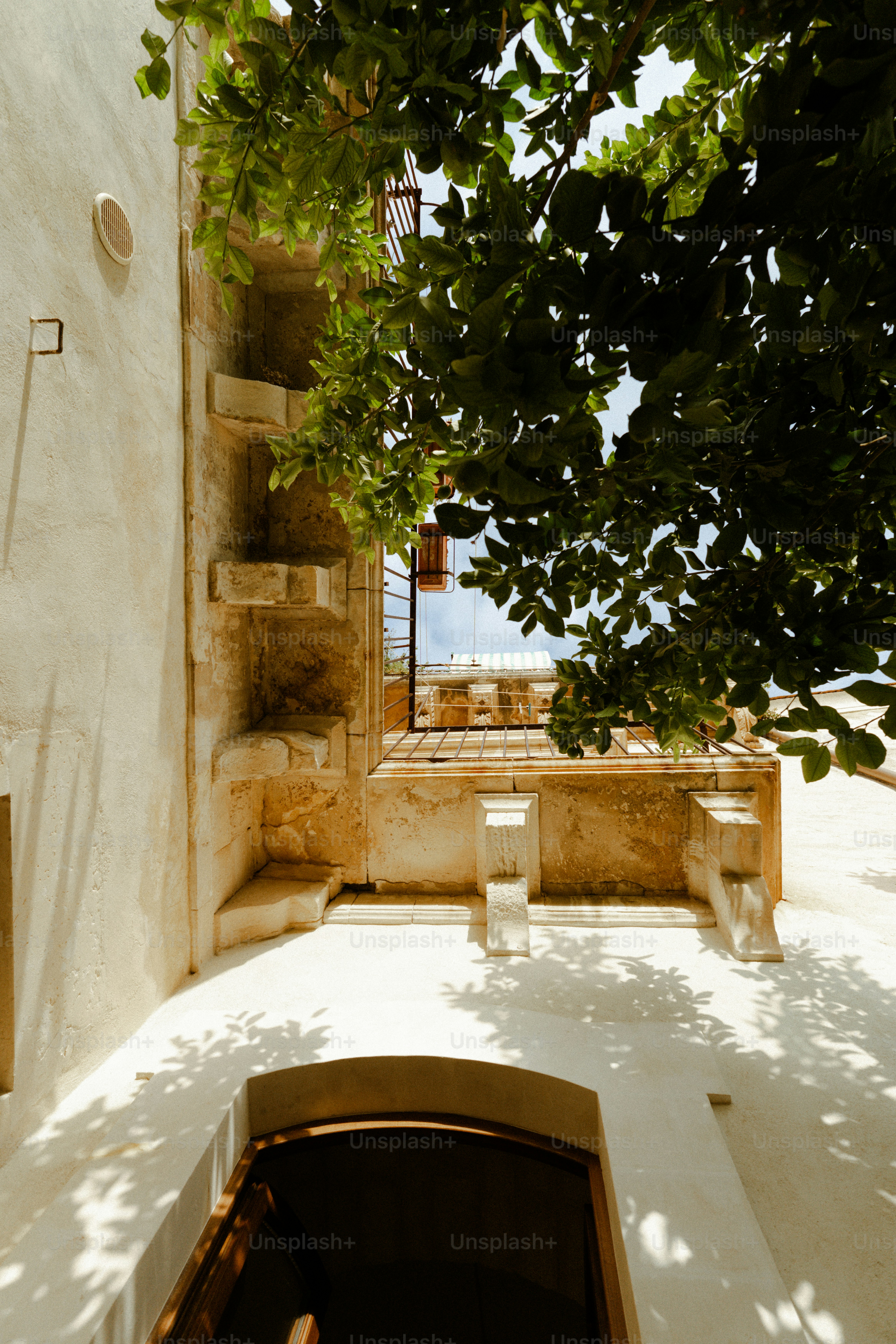 Innenhof mit steinernen Treppen und laubreichen Ästen