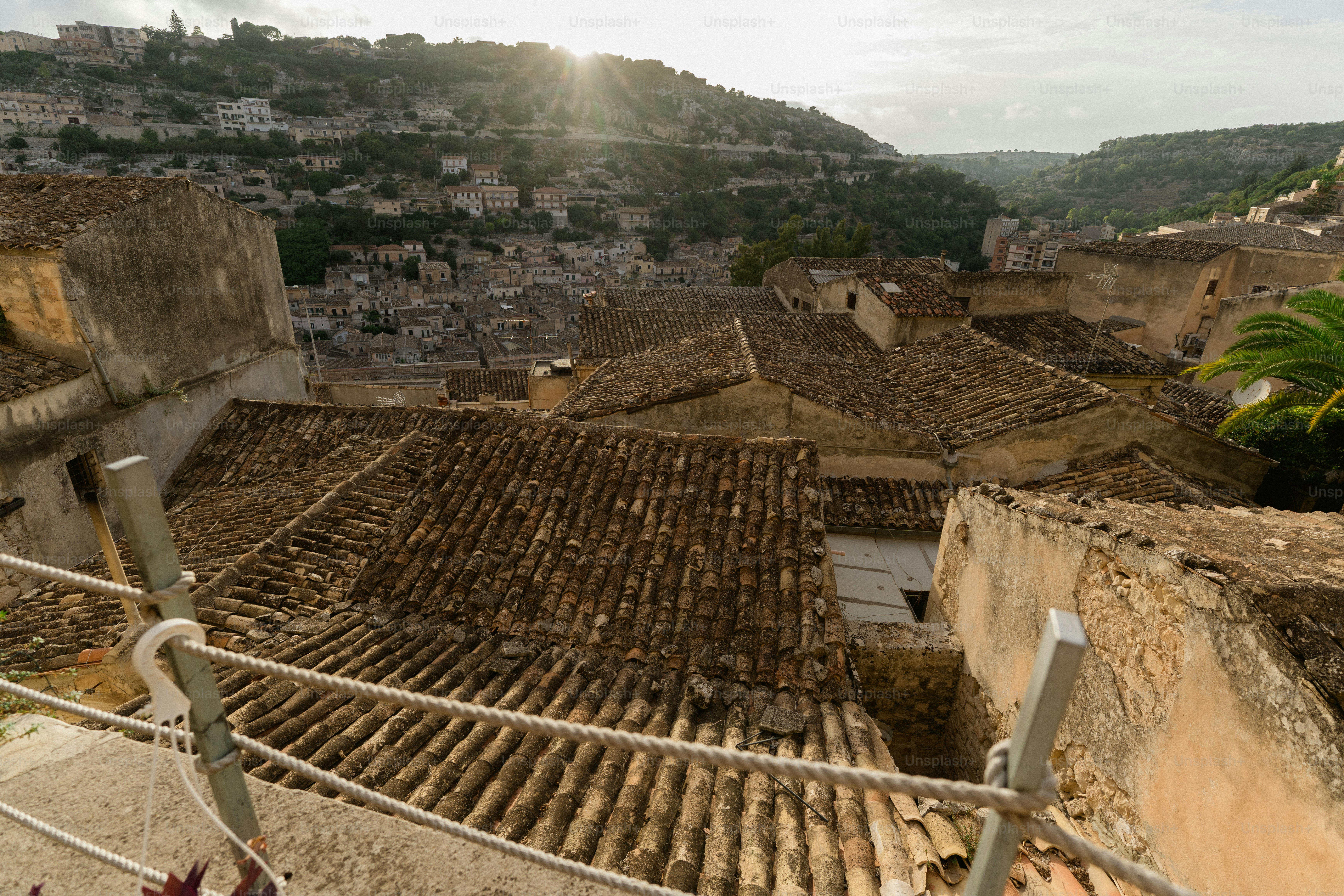 Dächer einer Altstadt mit Hügeln im Hintergrund.