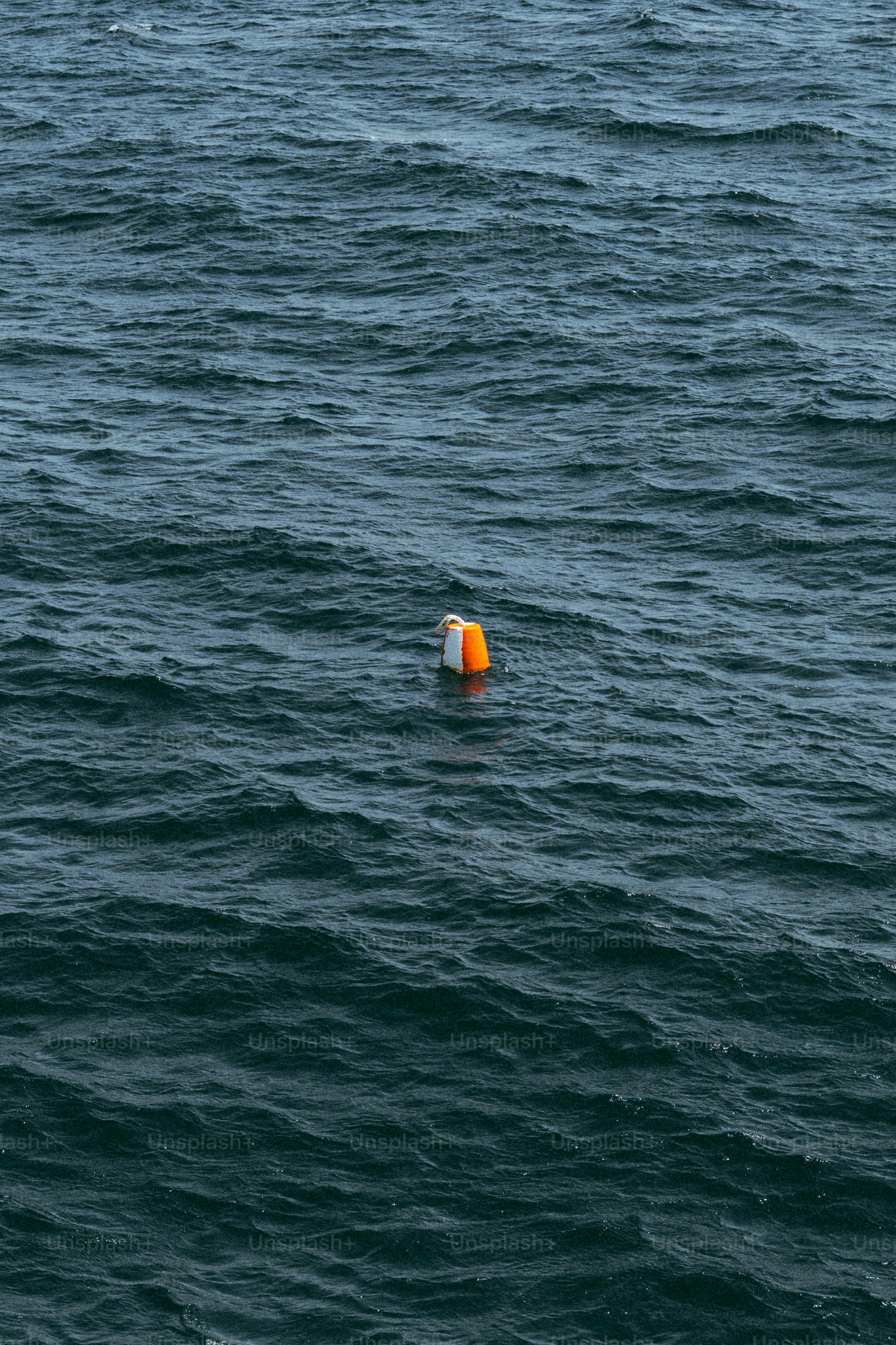 Bouée orange et blanche flottant sur des vagues bleu foncé