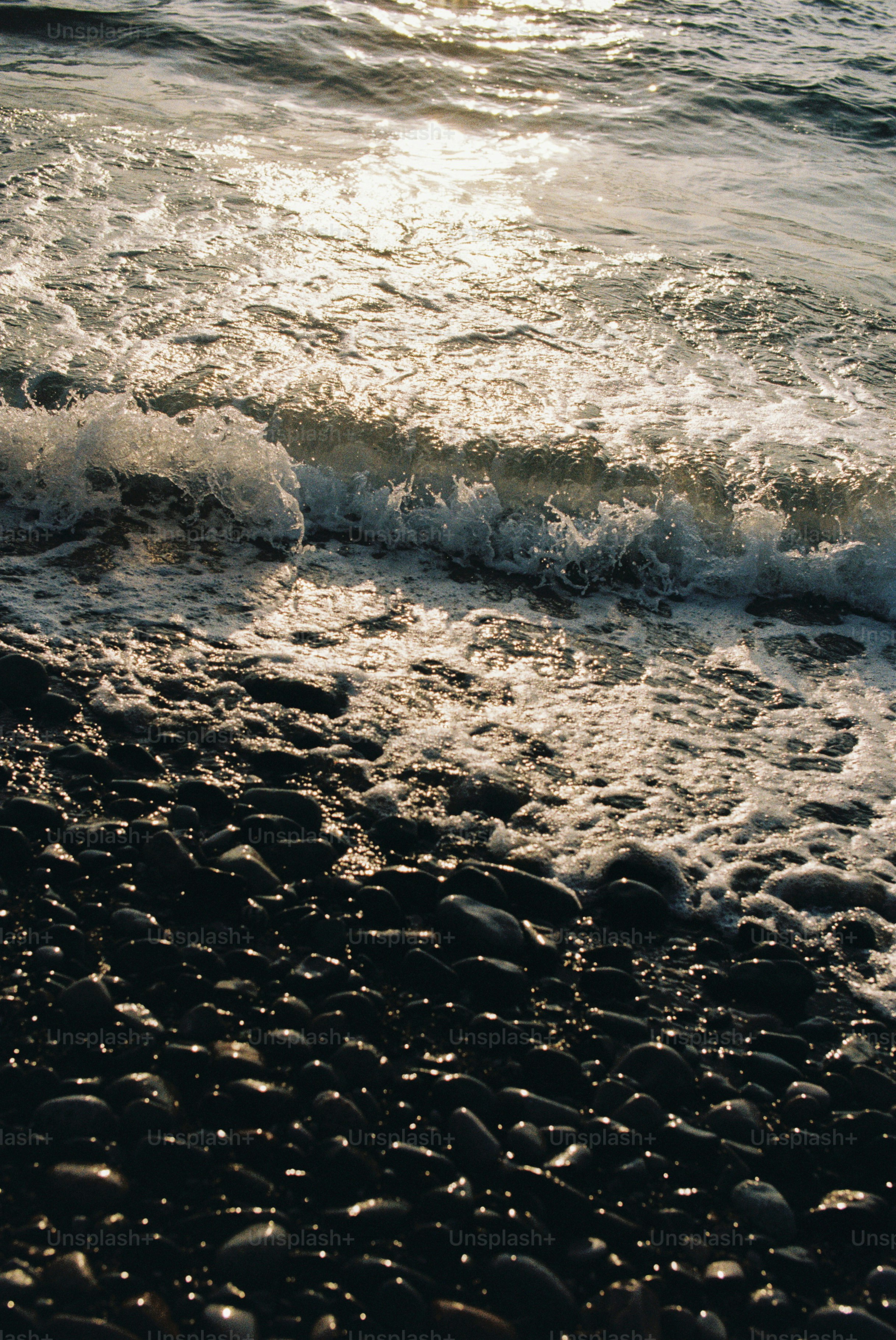 Waves crashing on a pebble beach at sunset