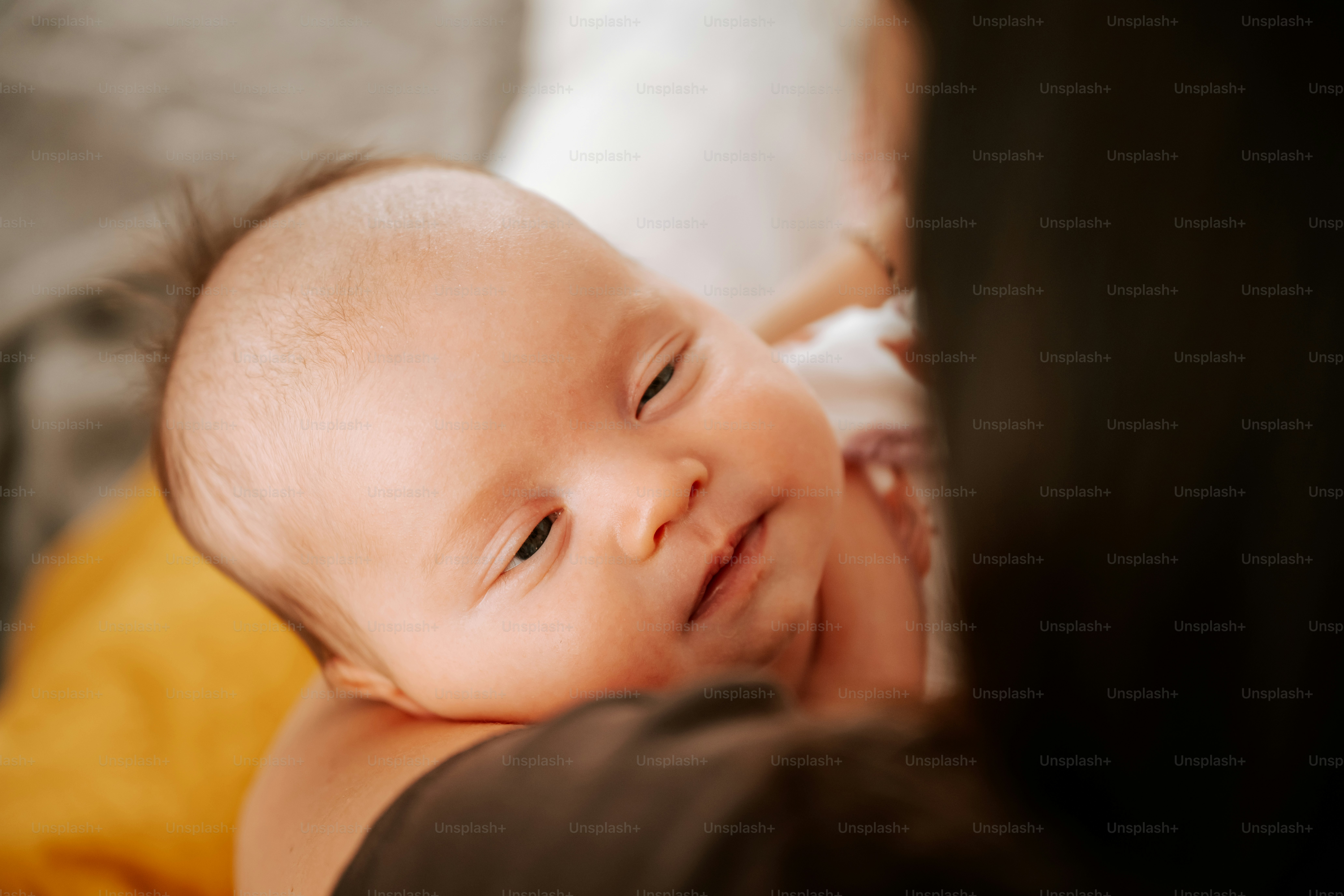 A newborn baby rests on a person's shoulder.