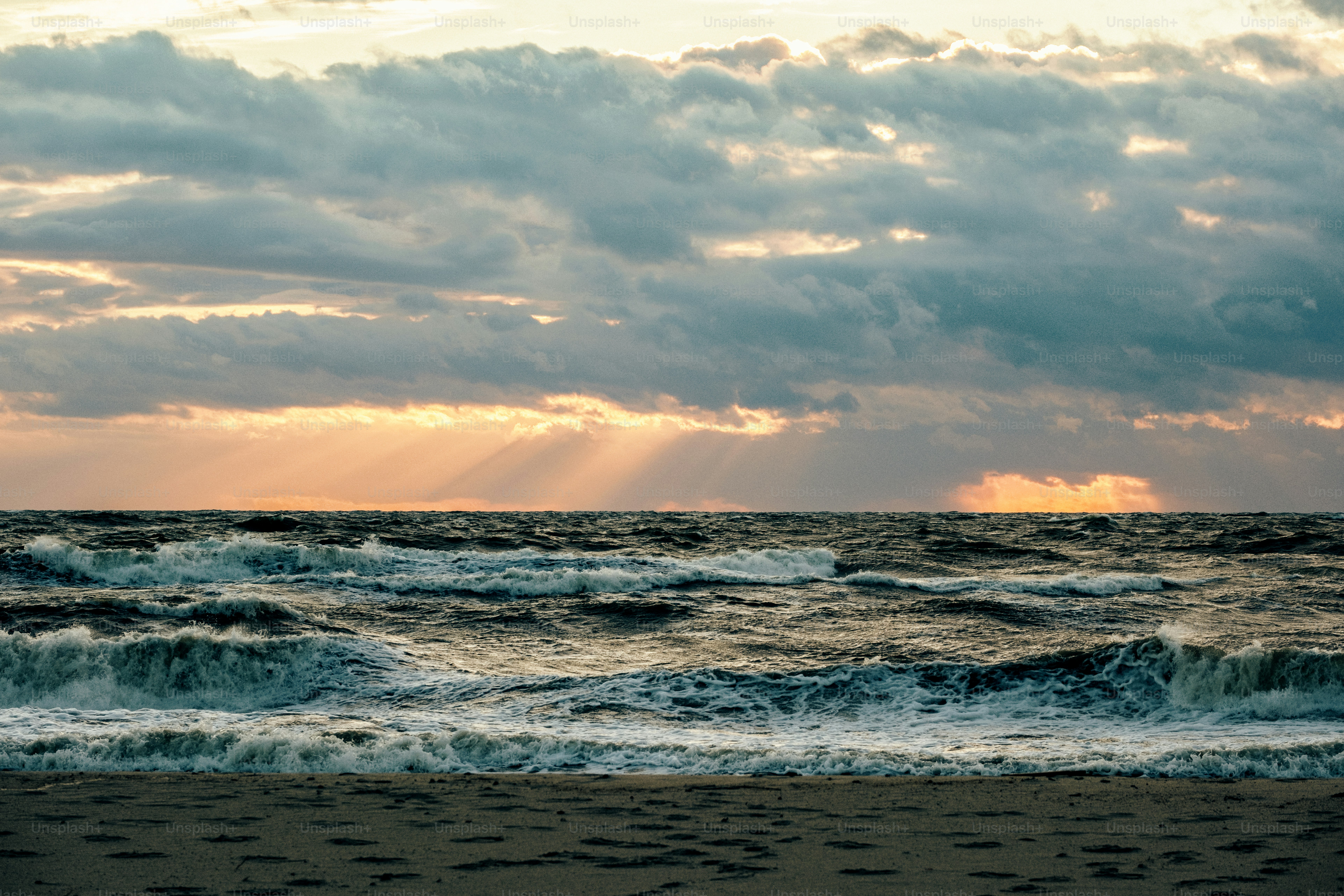 Sunbeams pierce through dramatic clouds over ocean waves. photo – Beach ...