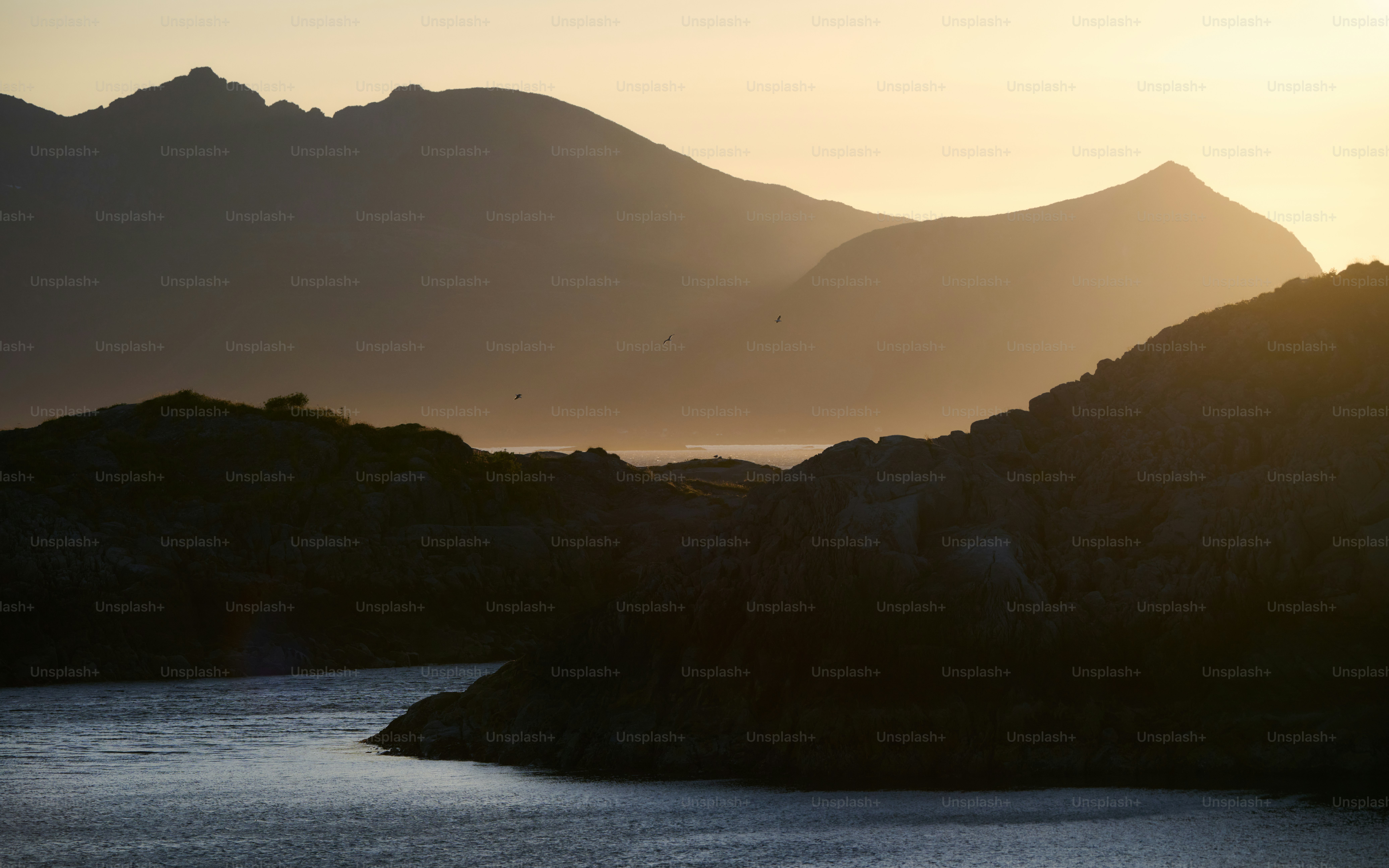 Silhouetted mountains with a calm body of water.