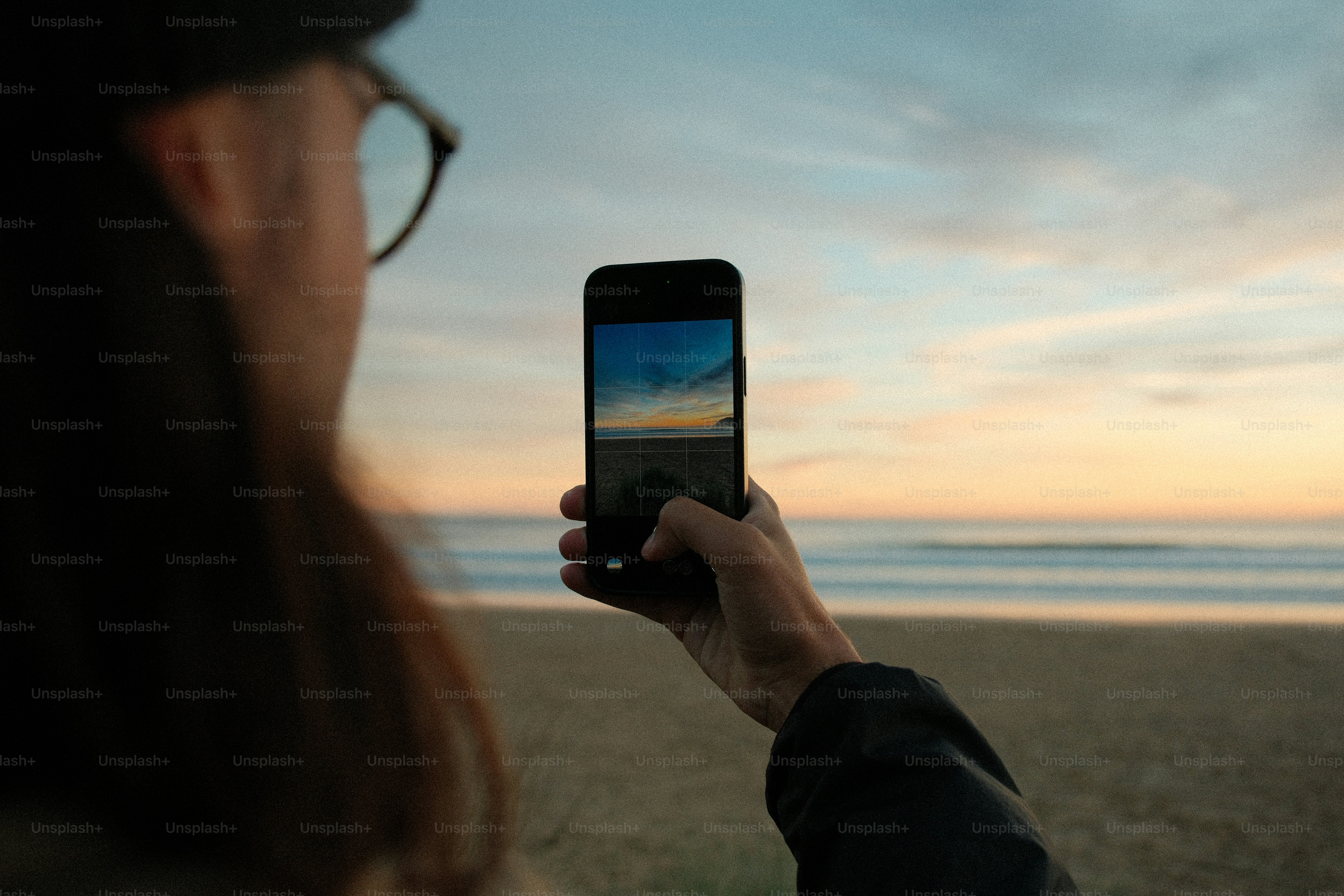 Personne prenant une photo de coucher de soleil sur une plage.