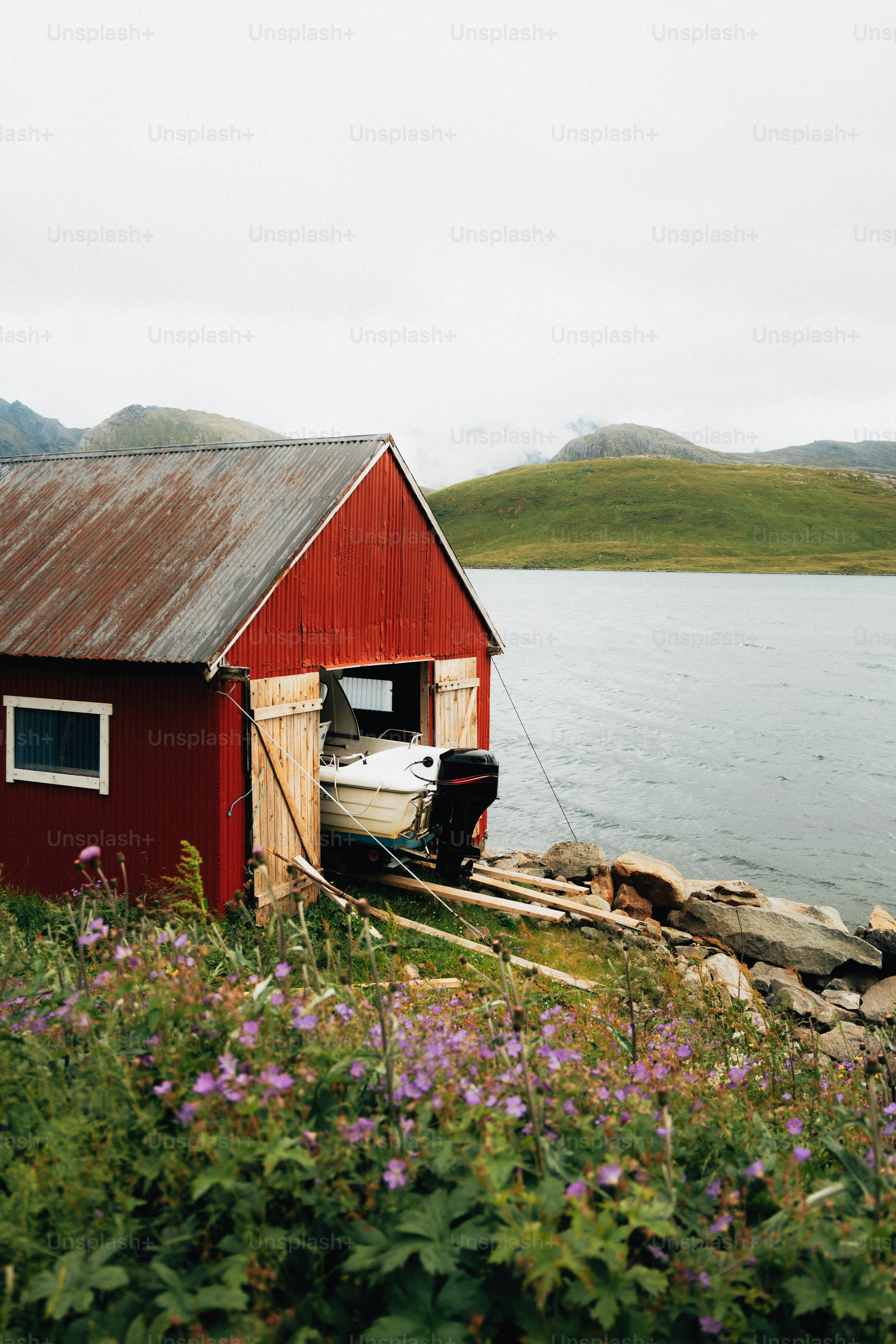 Hangar rouge sur un lac avec des montagnes