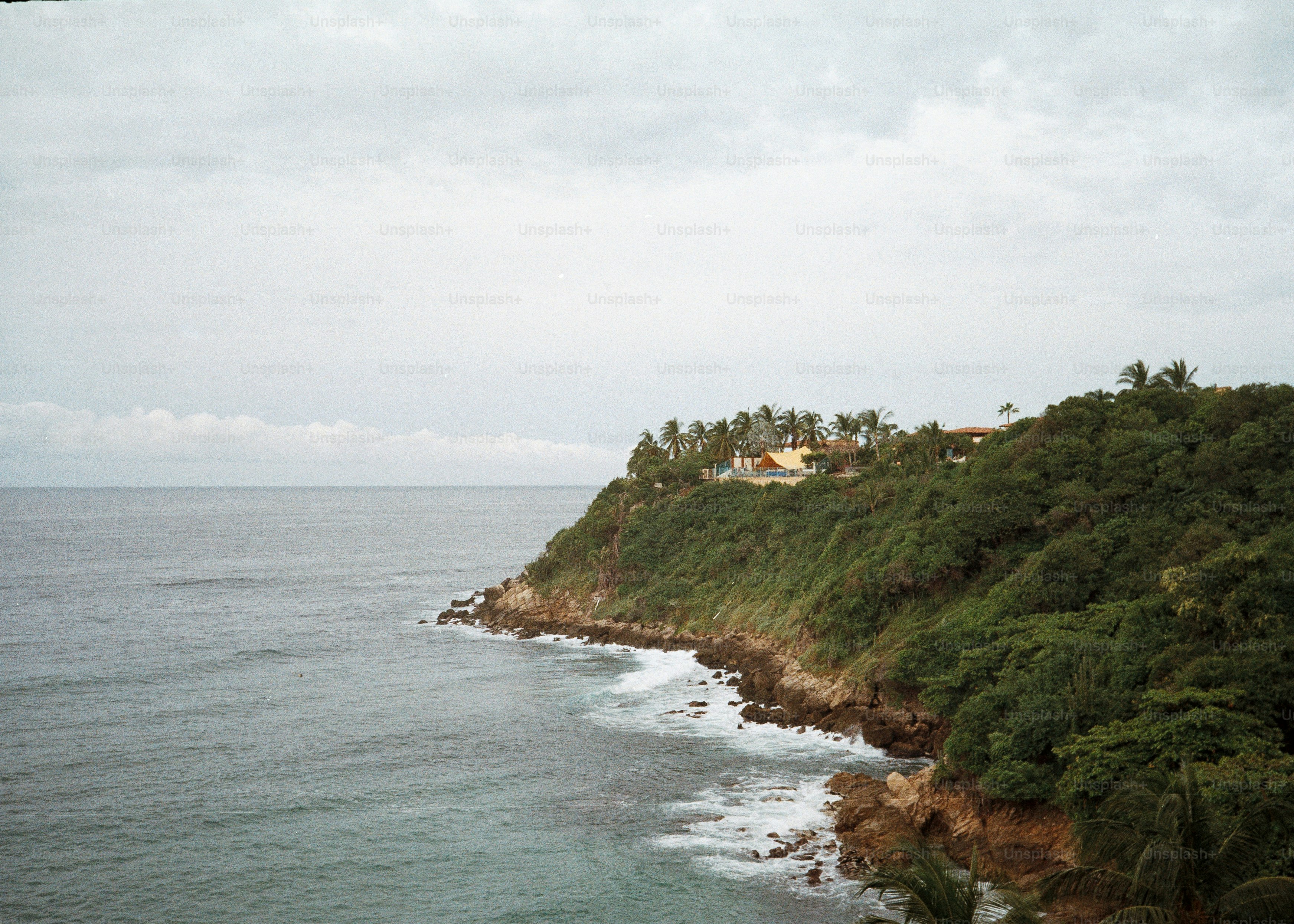 Green cliff overlooking the ocean under cloudy sky