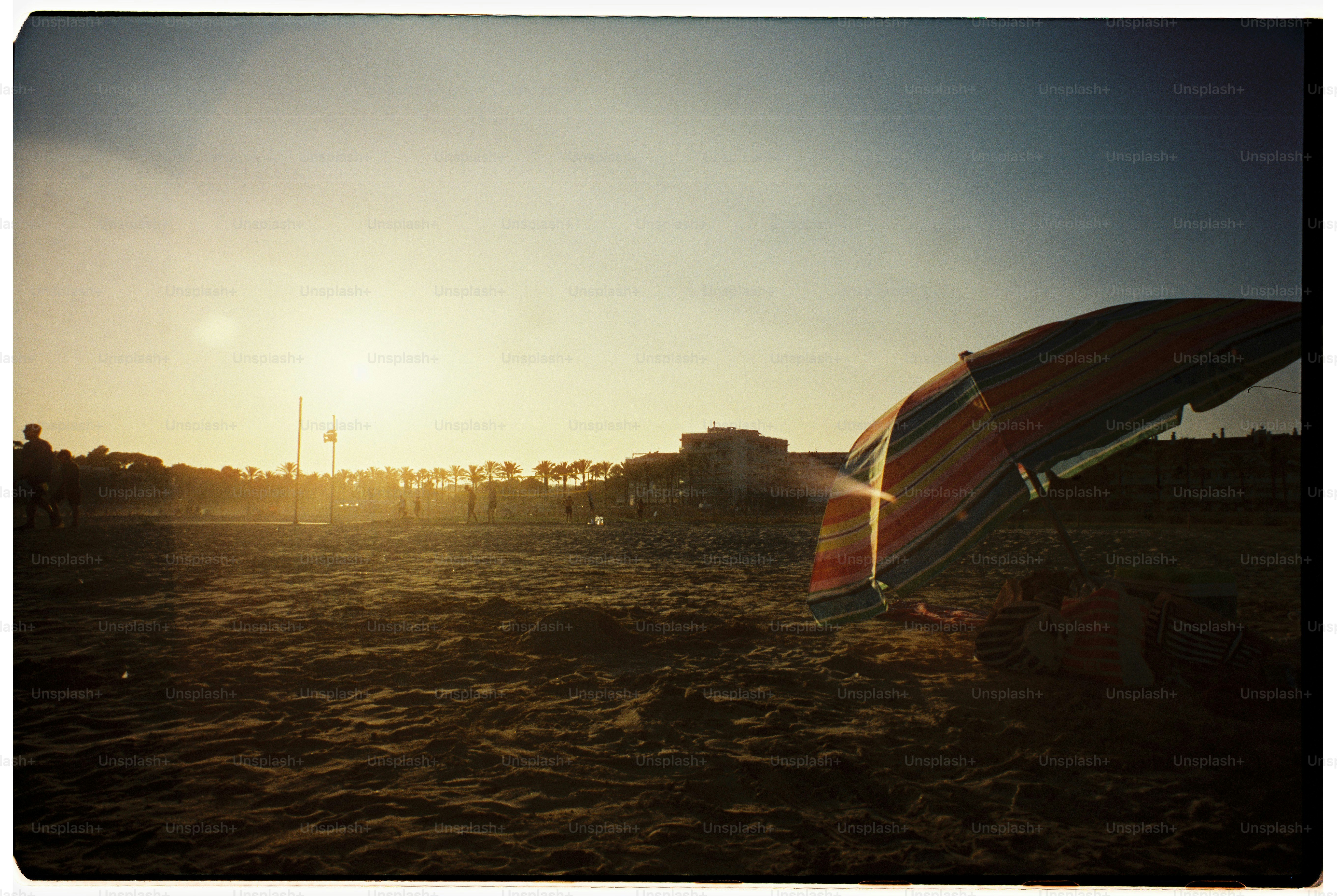 Parasol de plage au coucher du soleil avec des bâtiments éloignés
