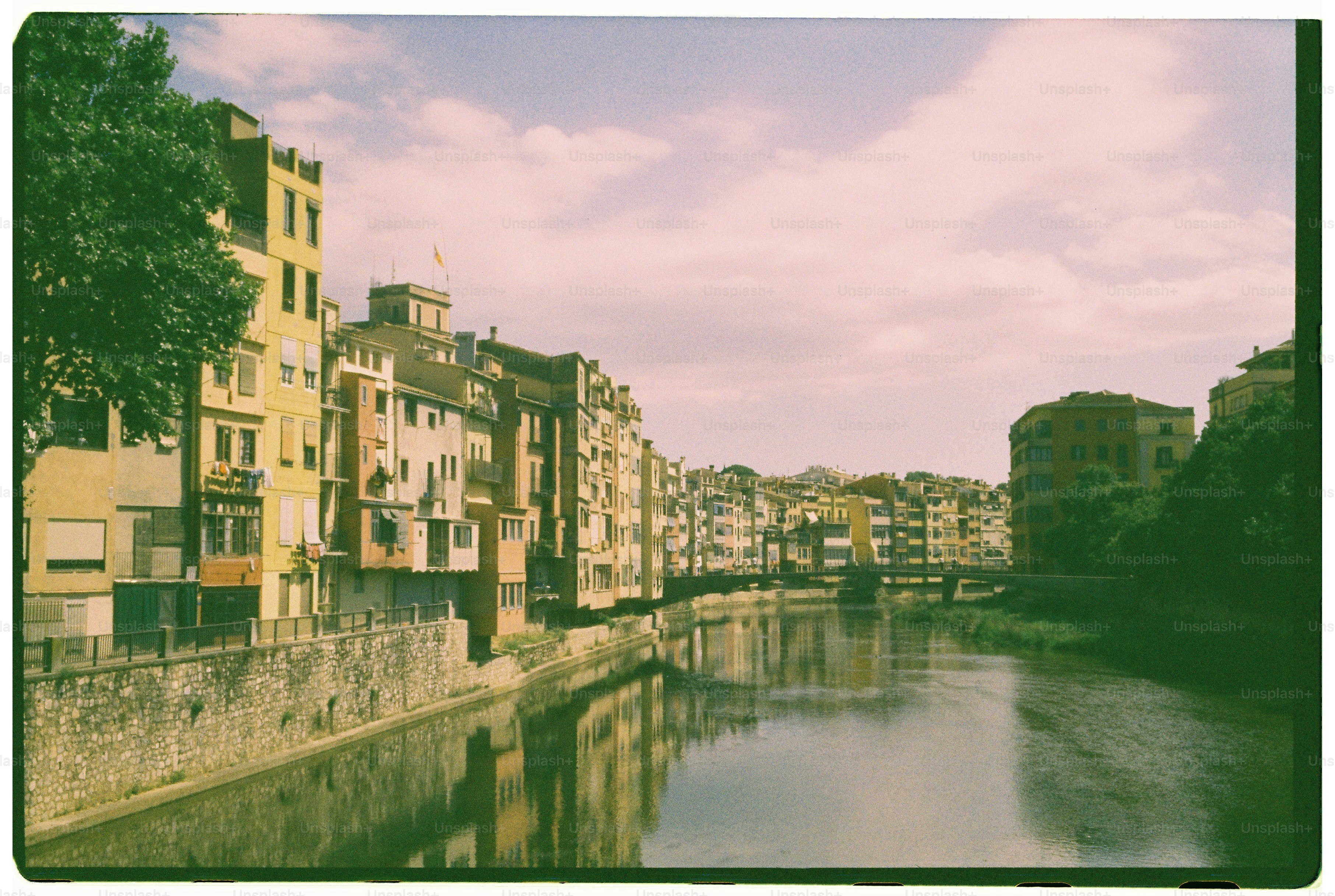 Des bâtiments bordant une rivière avec un pont au loin.