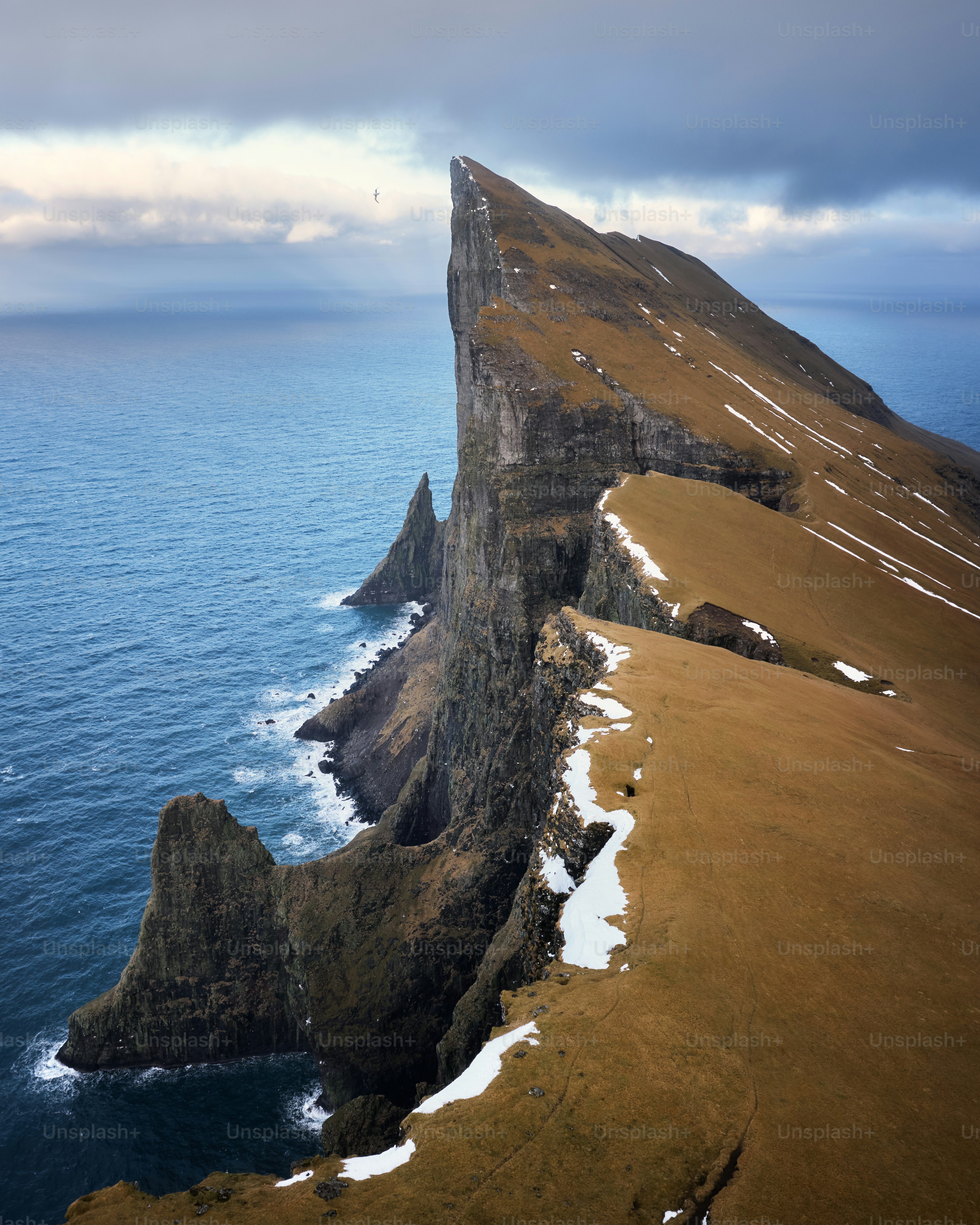 Dramatische Klippen erheben sich aus dem Ozean unter einem bewölkten Himmel.