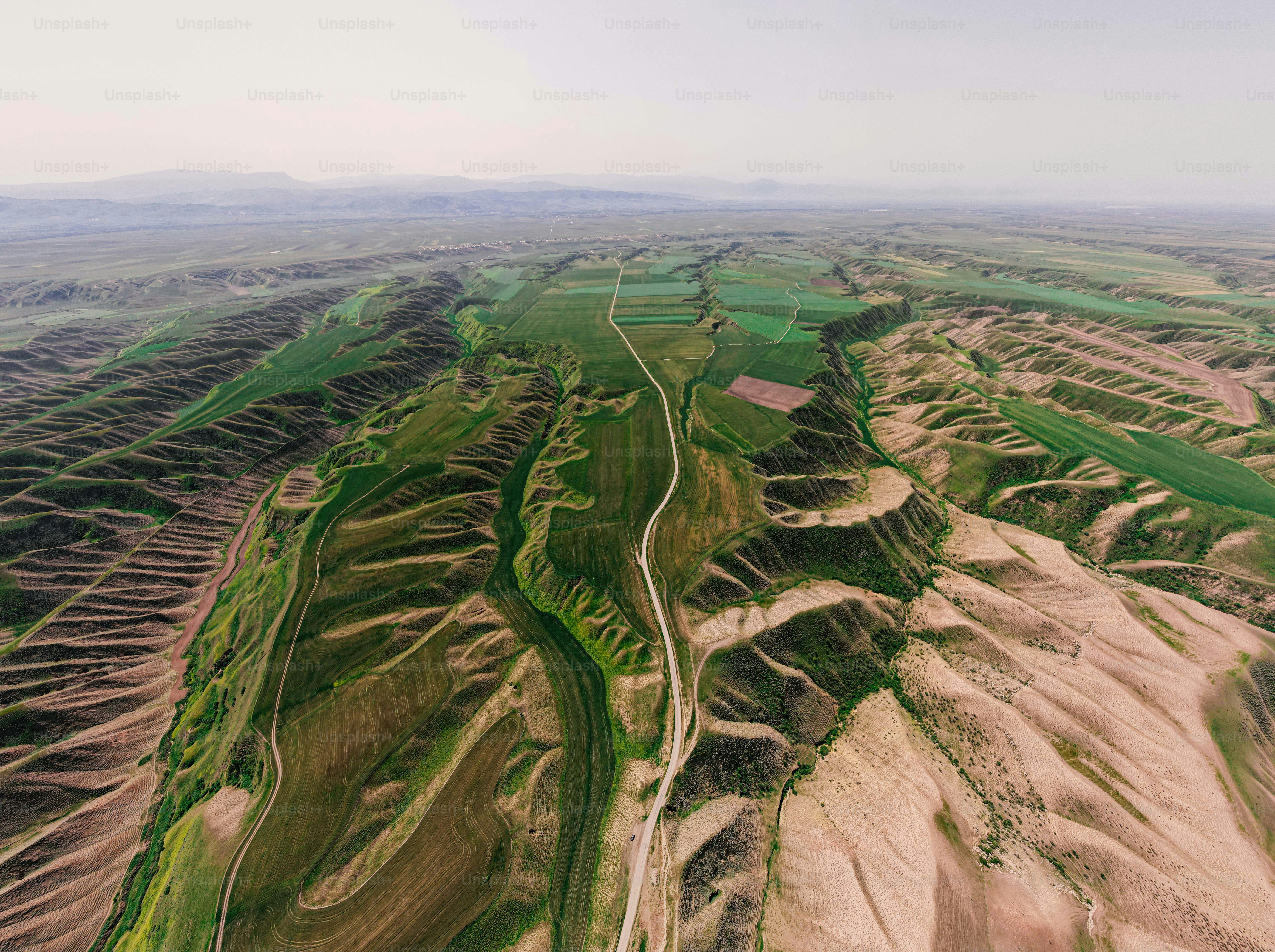 Vista aérea de uma estrada sinuosa por colinas verdes e ondulantes
