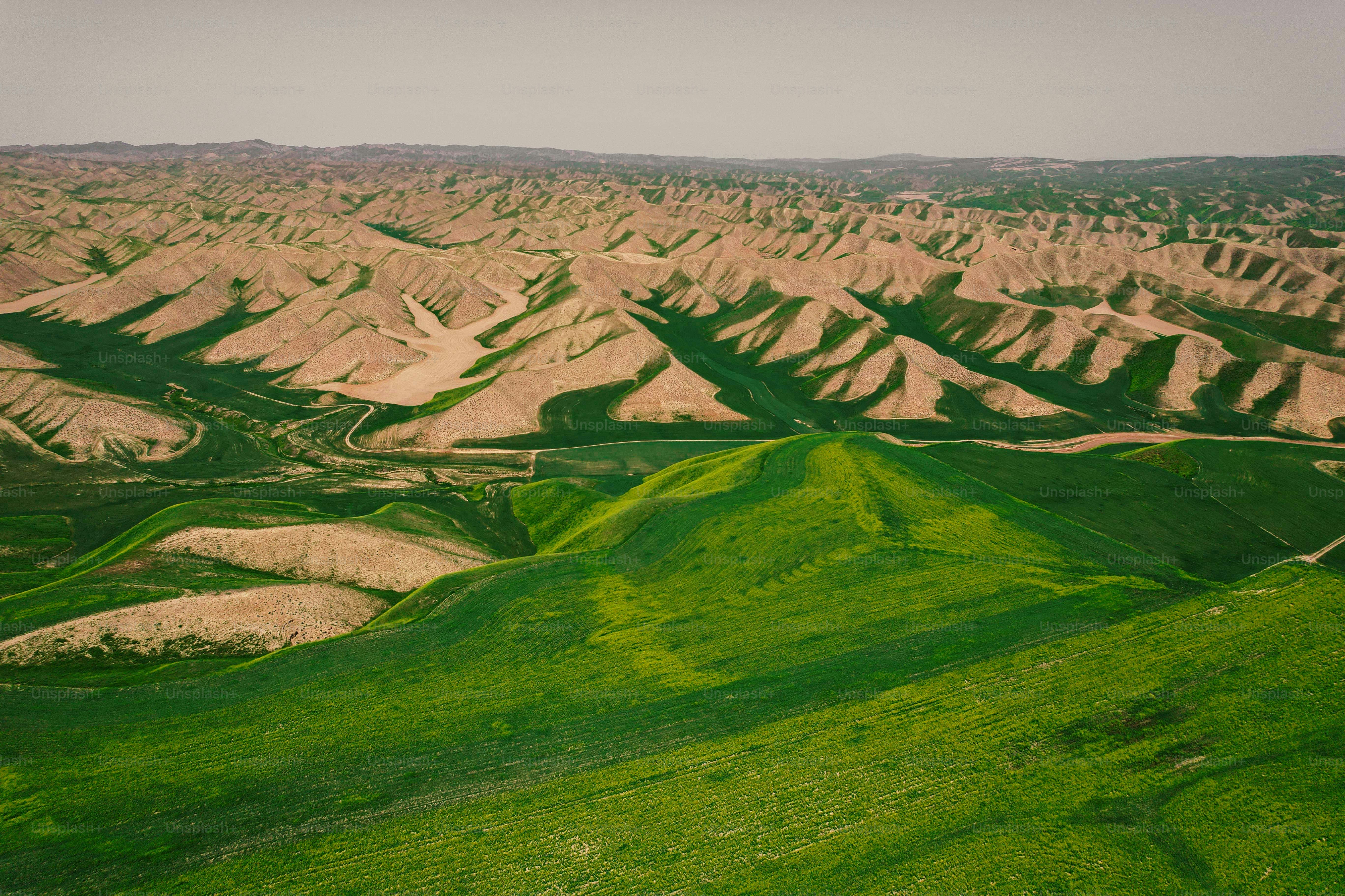 Rolling green hills meet arid, eroded landscape