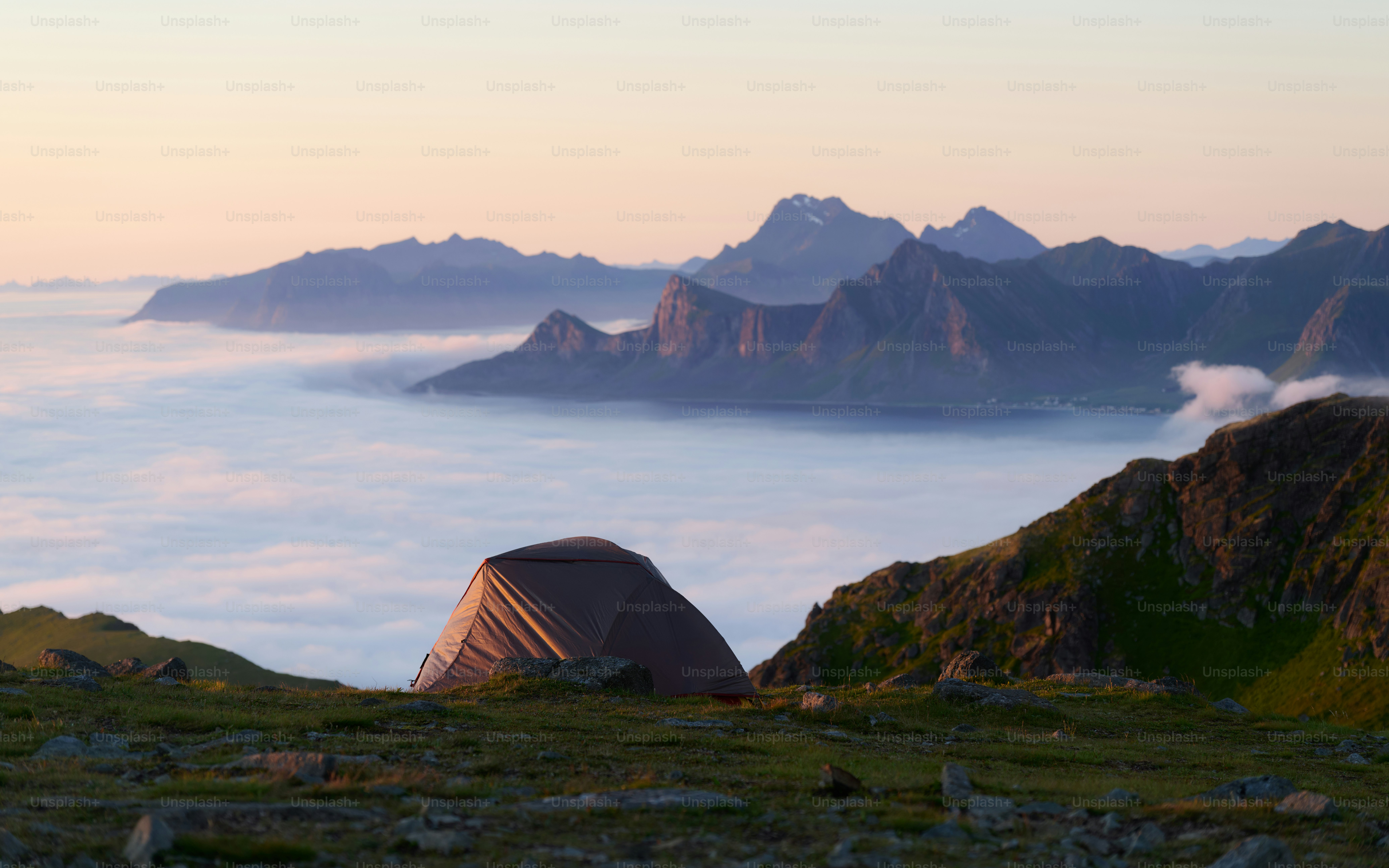 Zelt auf einem grasbewachsenen Berg über den Wolken aufgeschlagen