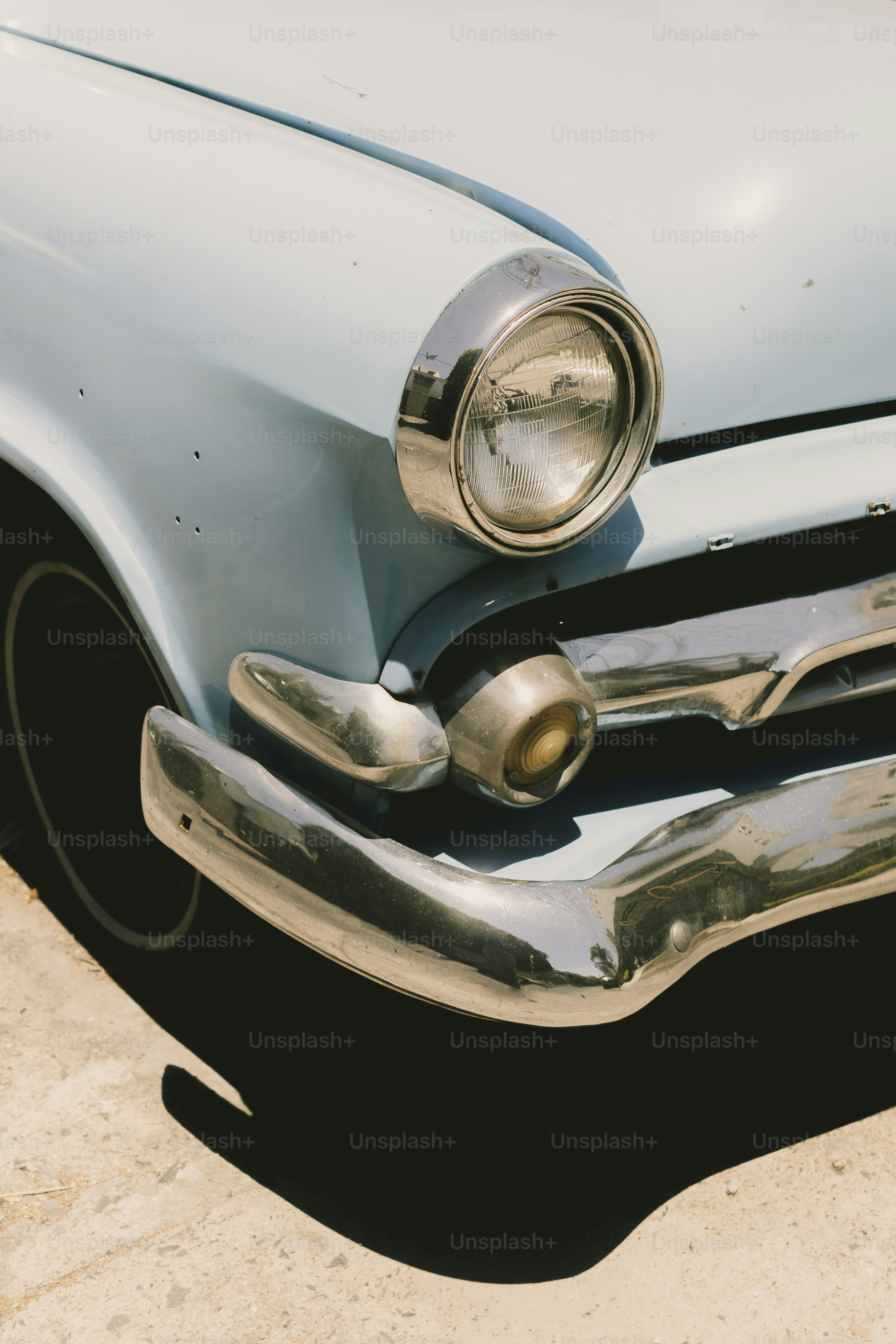 Close do farol de um carro azul claro vintage.