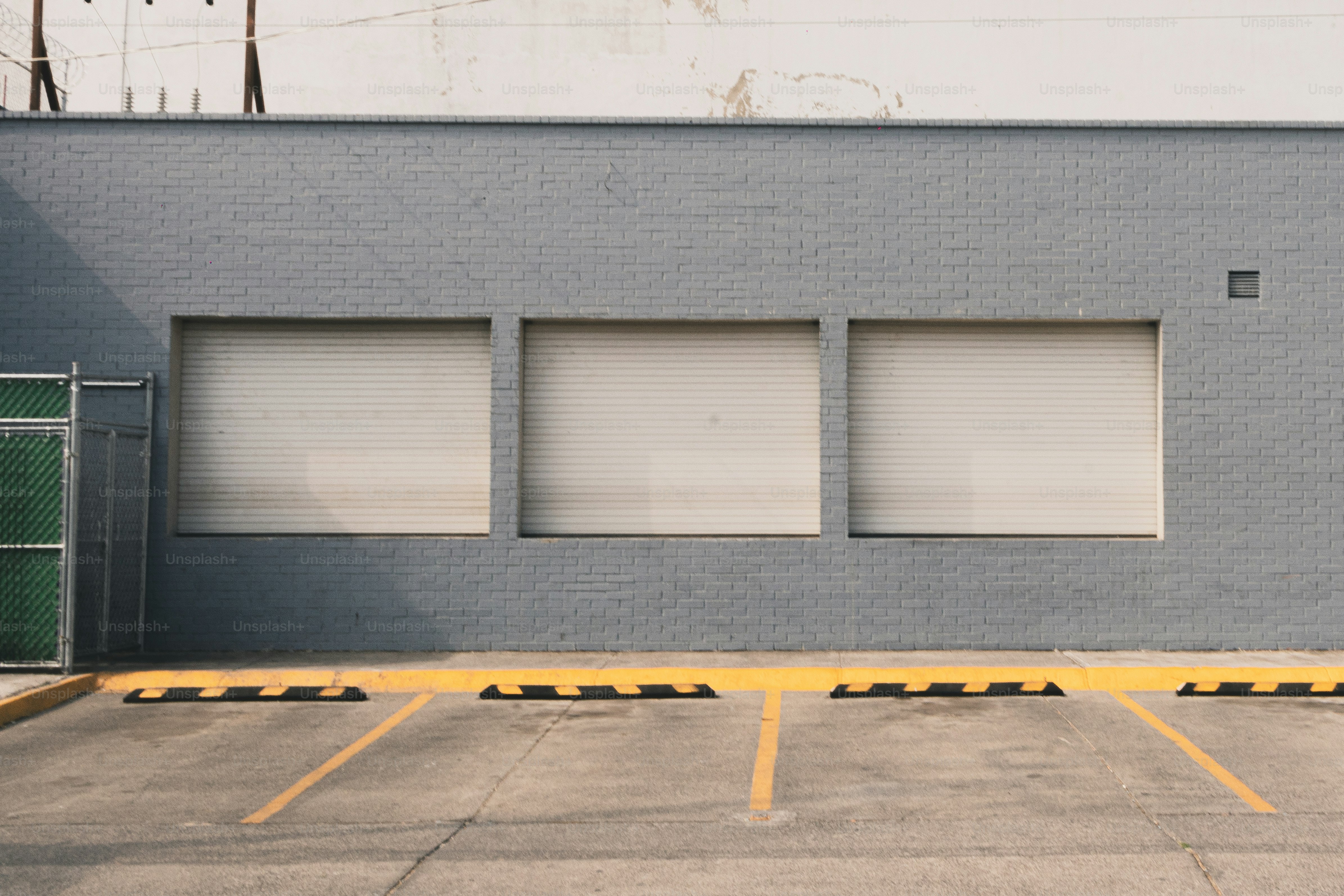 Three blank garage doors on a gray building.