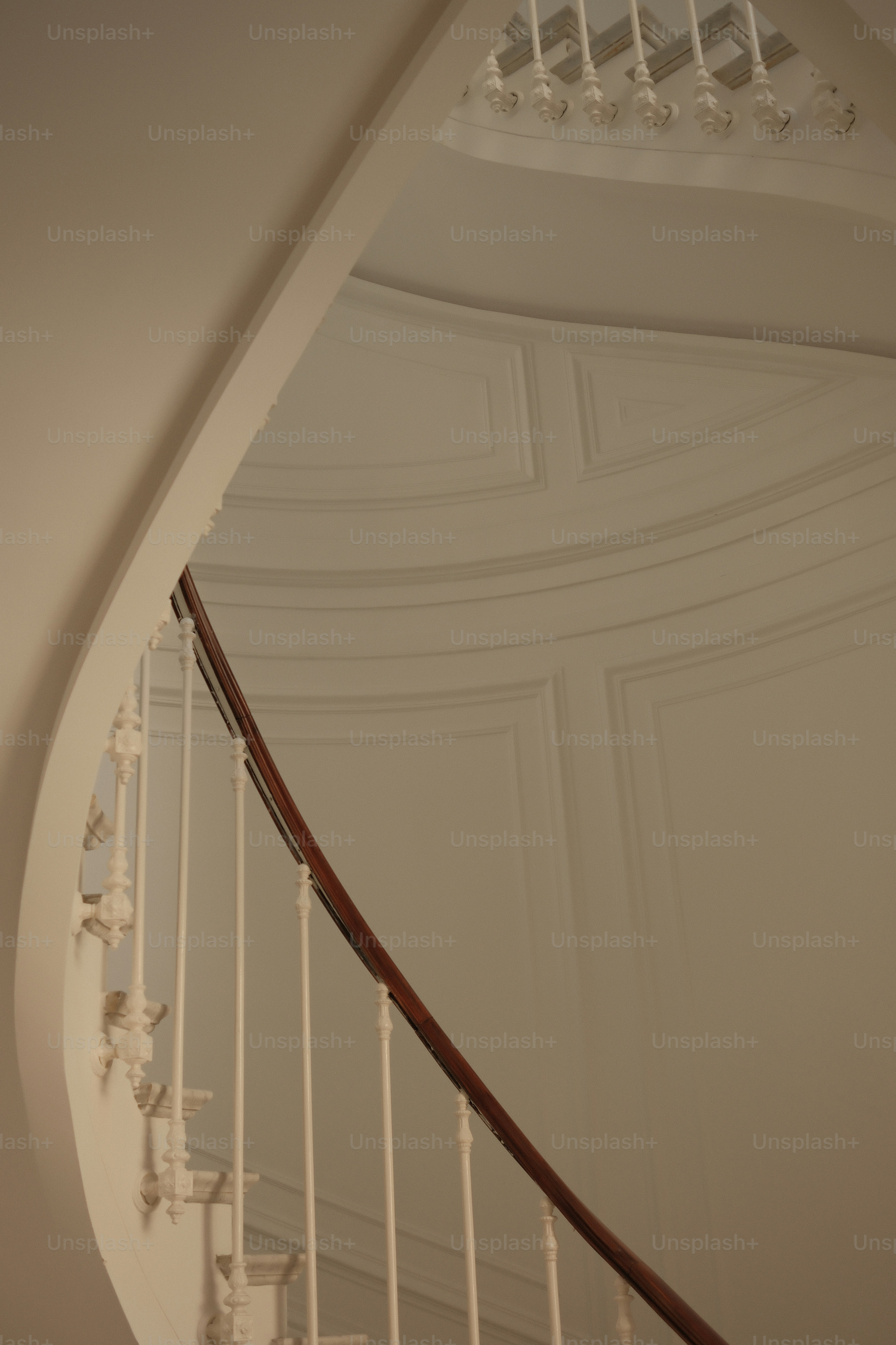 Elegante escalera de caracol blanca con pasamanos de madera.