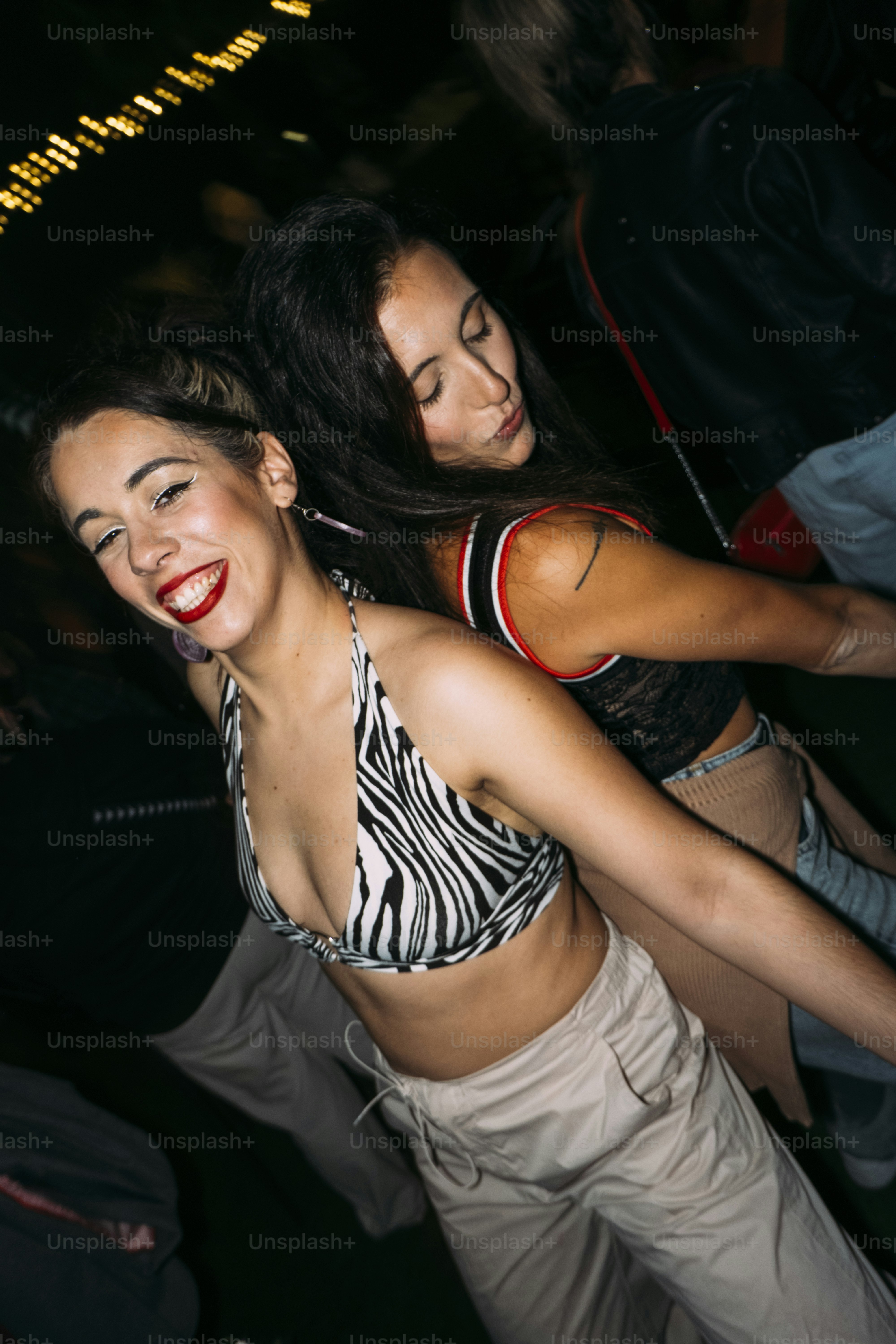 Two women dancing at a party at night.
