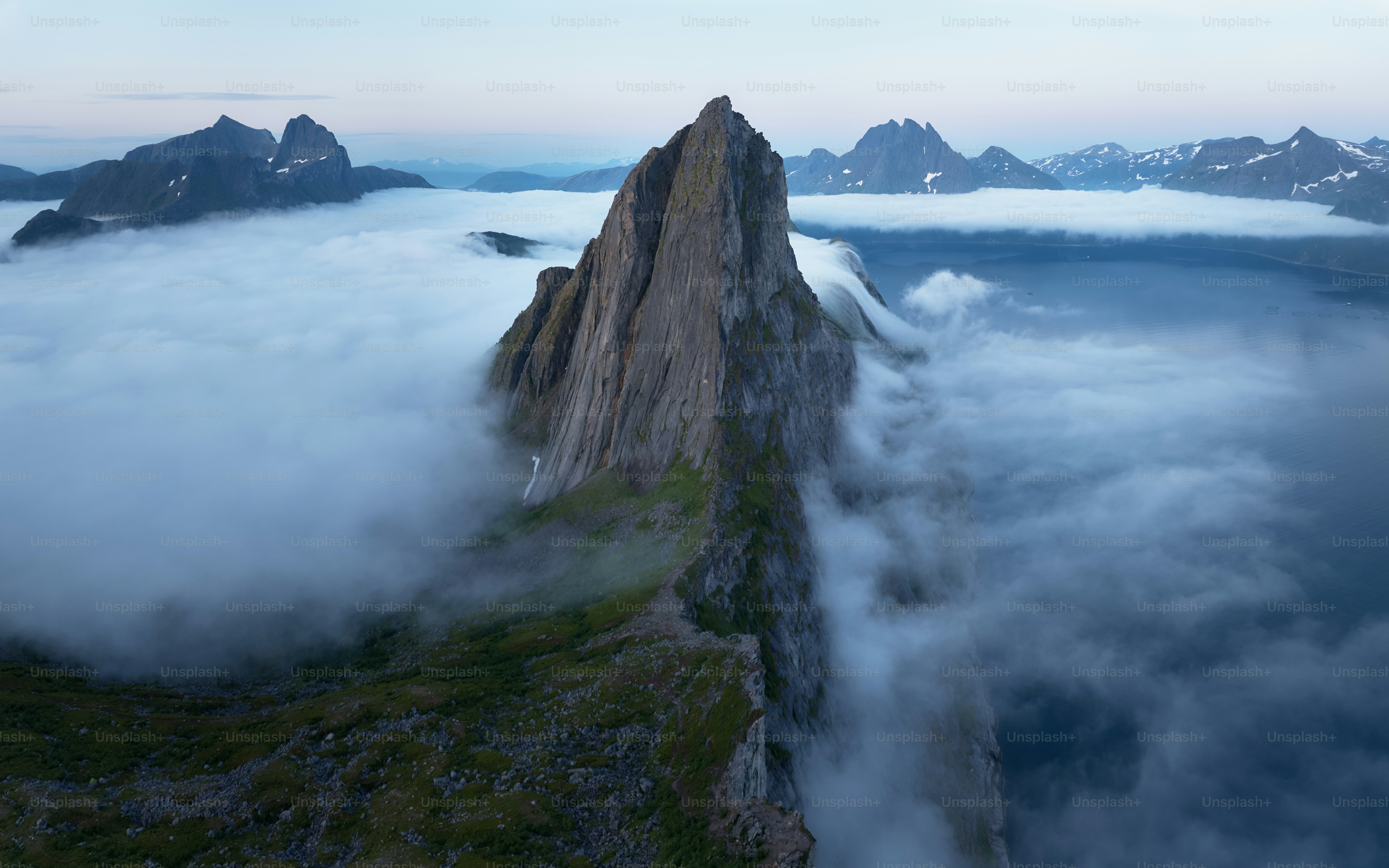 Gezackte Berggipfel ragen aus niedrig liegenden Wolken empor.