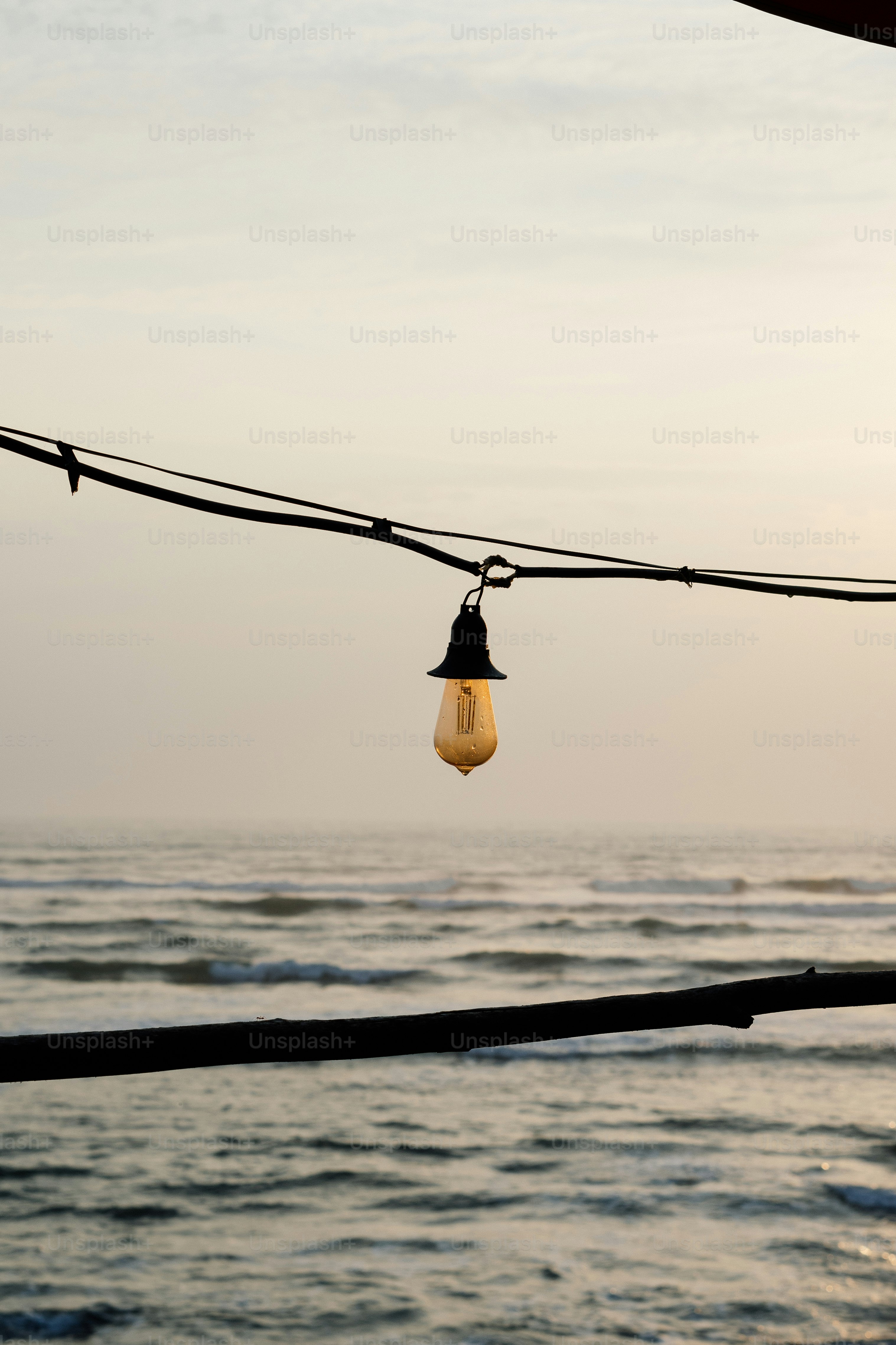 Single light bulb hangs over ocean waves