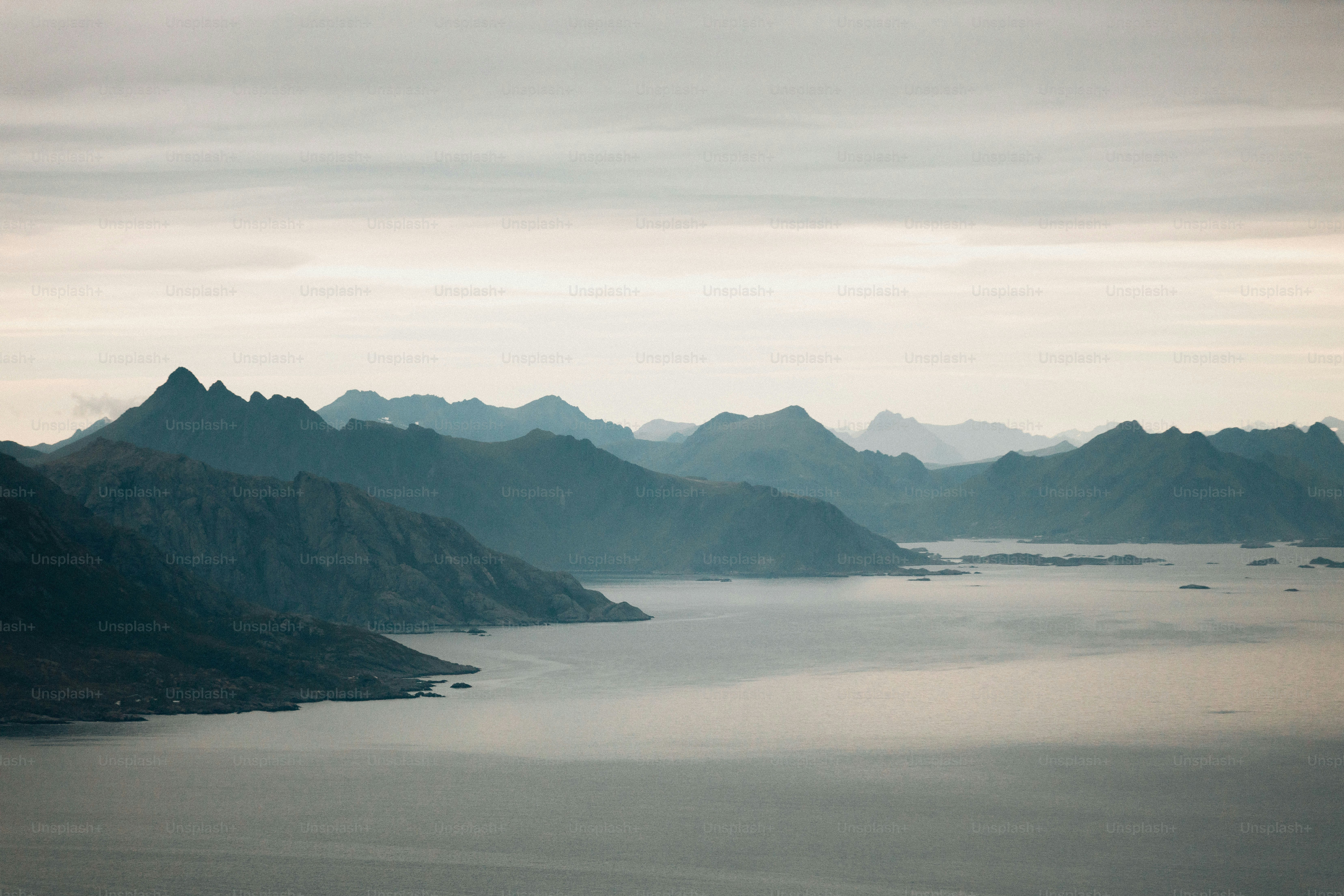 Neblige Berge erheben sich über ein ruhiges Meer.