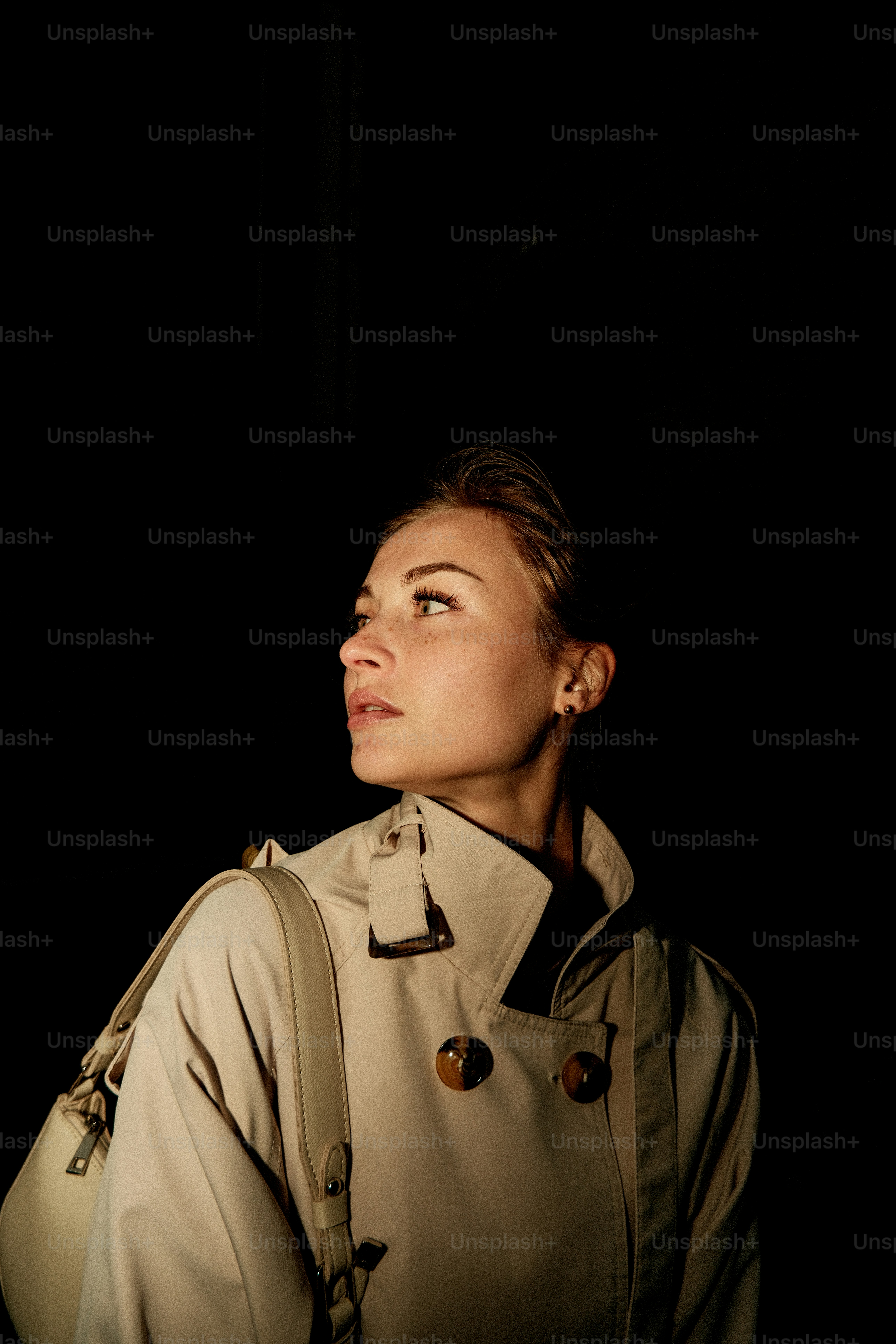 트렌치코트를 입은 여성이 좌우로 시선을 돌리고 있습니다.