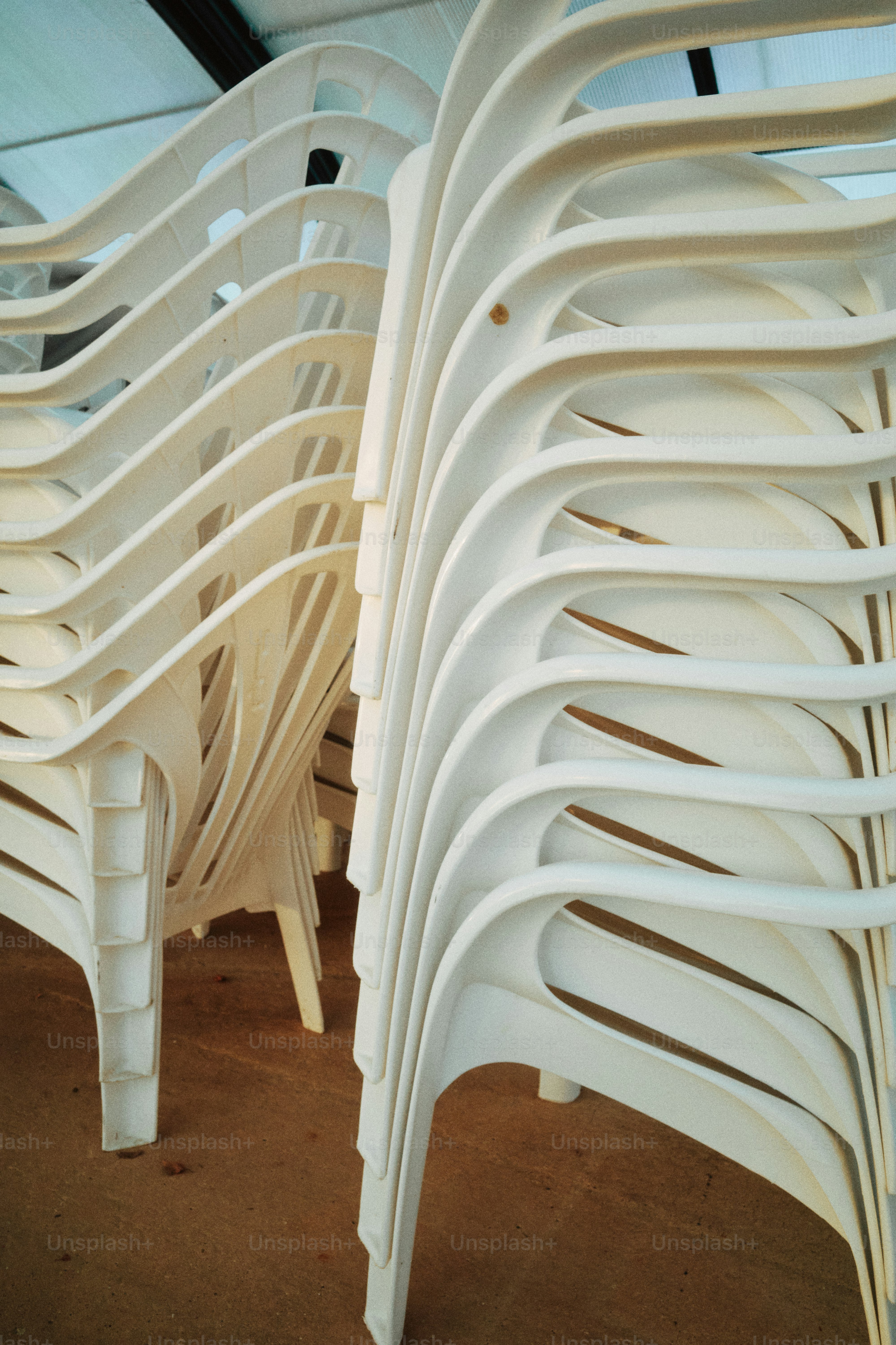 Stack of white plastic lounge chairs indoors