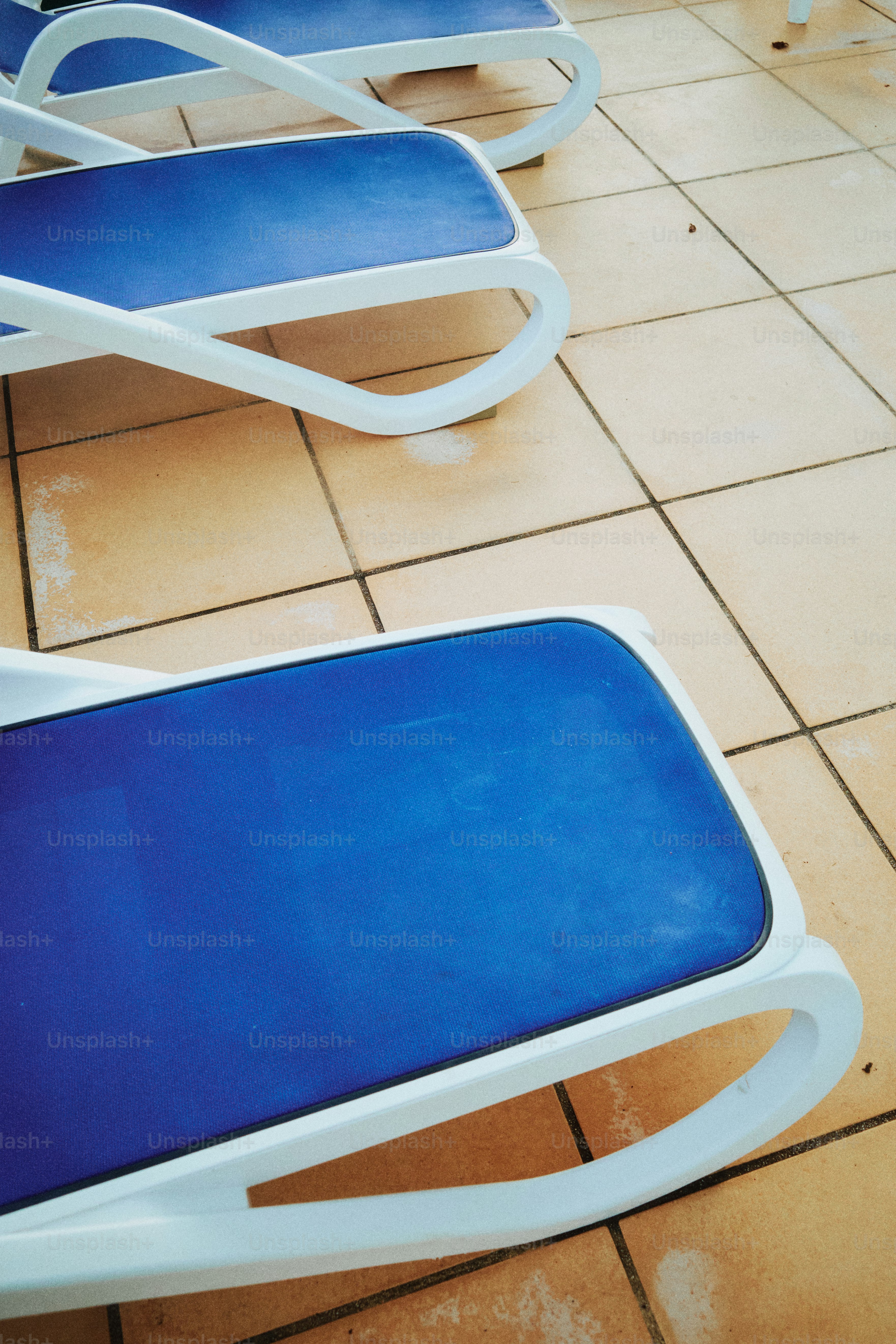 Chaises longues bleues sur un sol carrelé.
