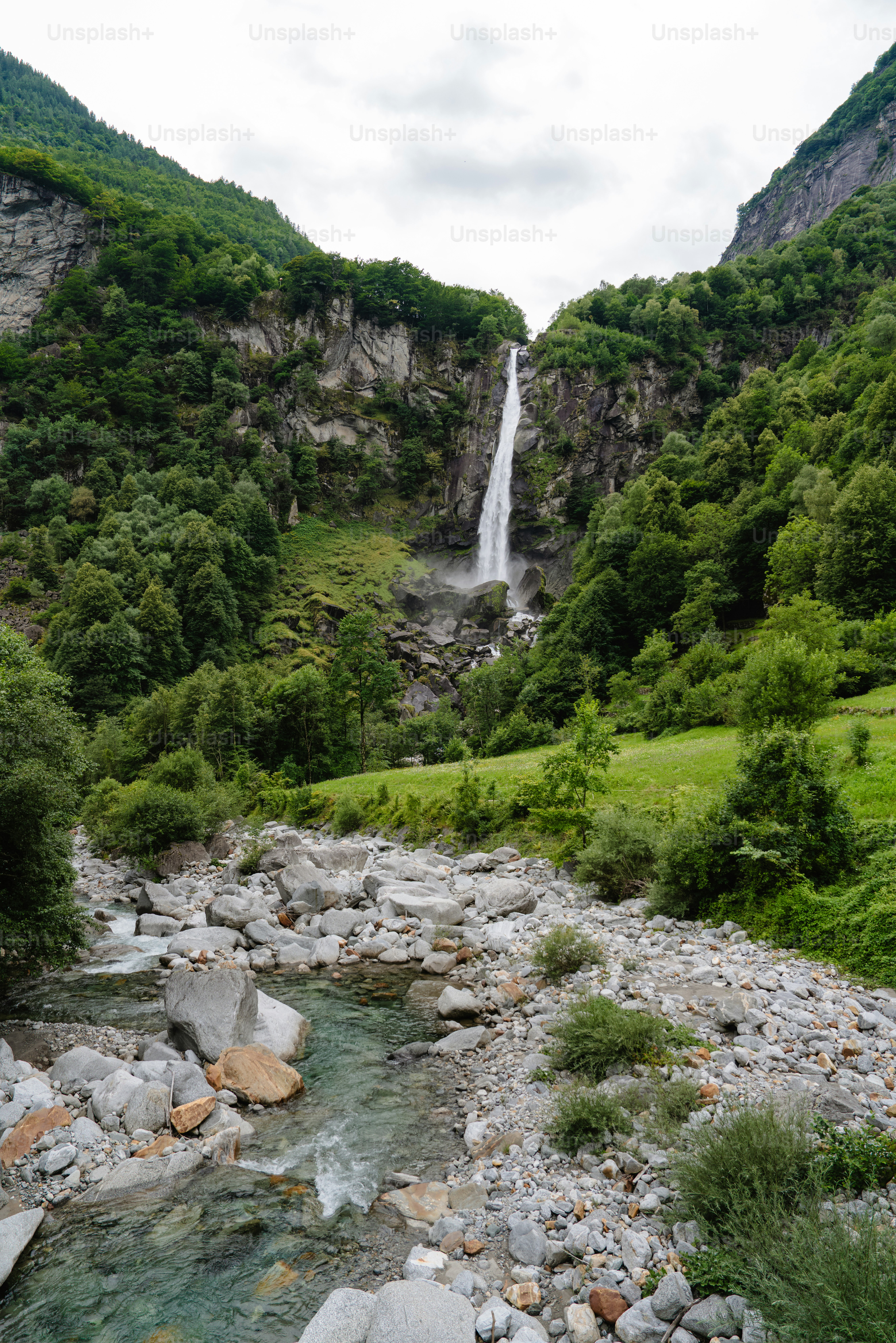 Tall waterfall cascades down a lush green mountainside.